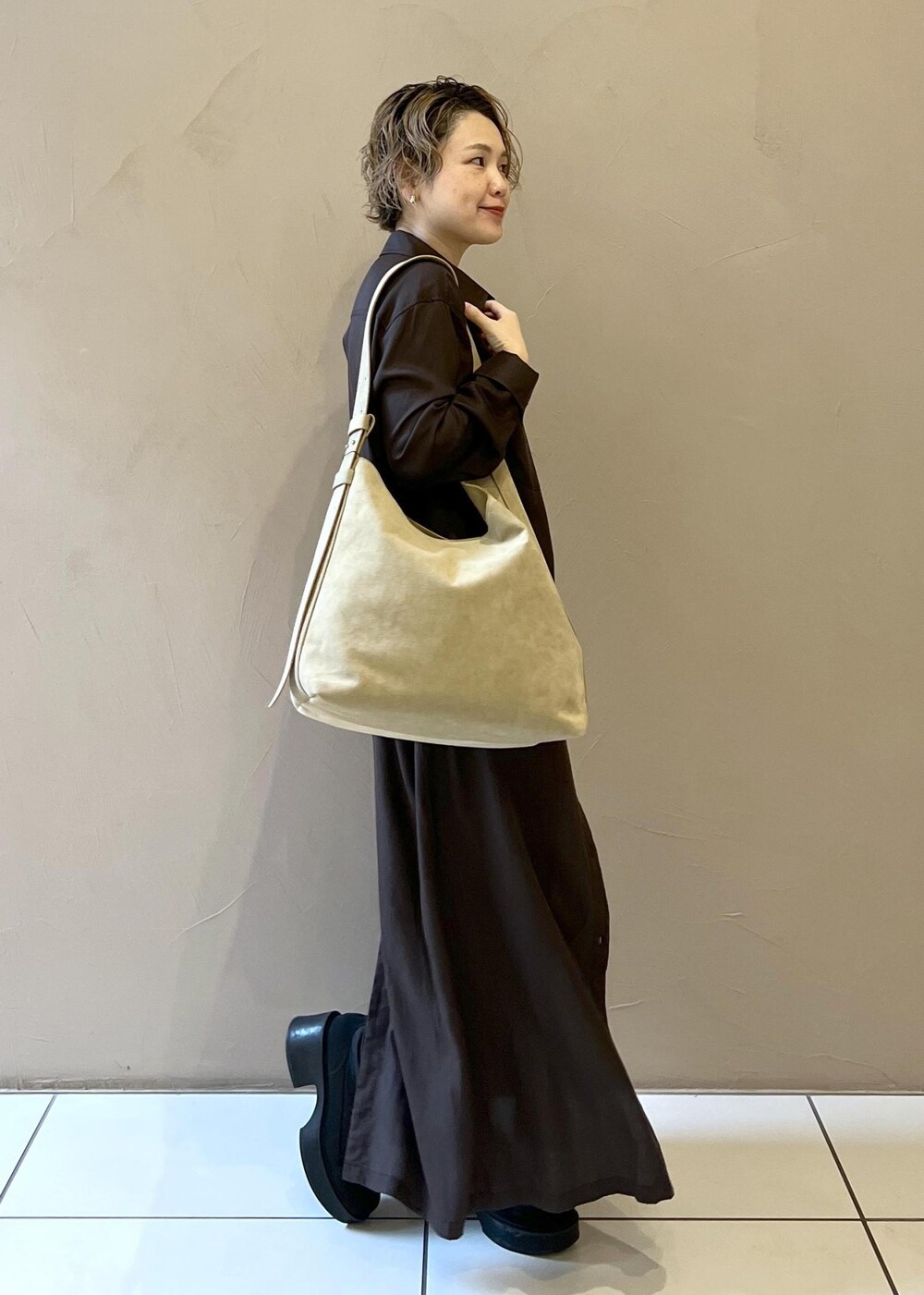 ベージュ系のショルダーバッグ、グレー系のワンピース、ブラック系のブーツを着用したレディースの秋コーディネートの7枚目の写真