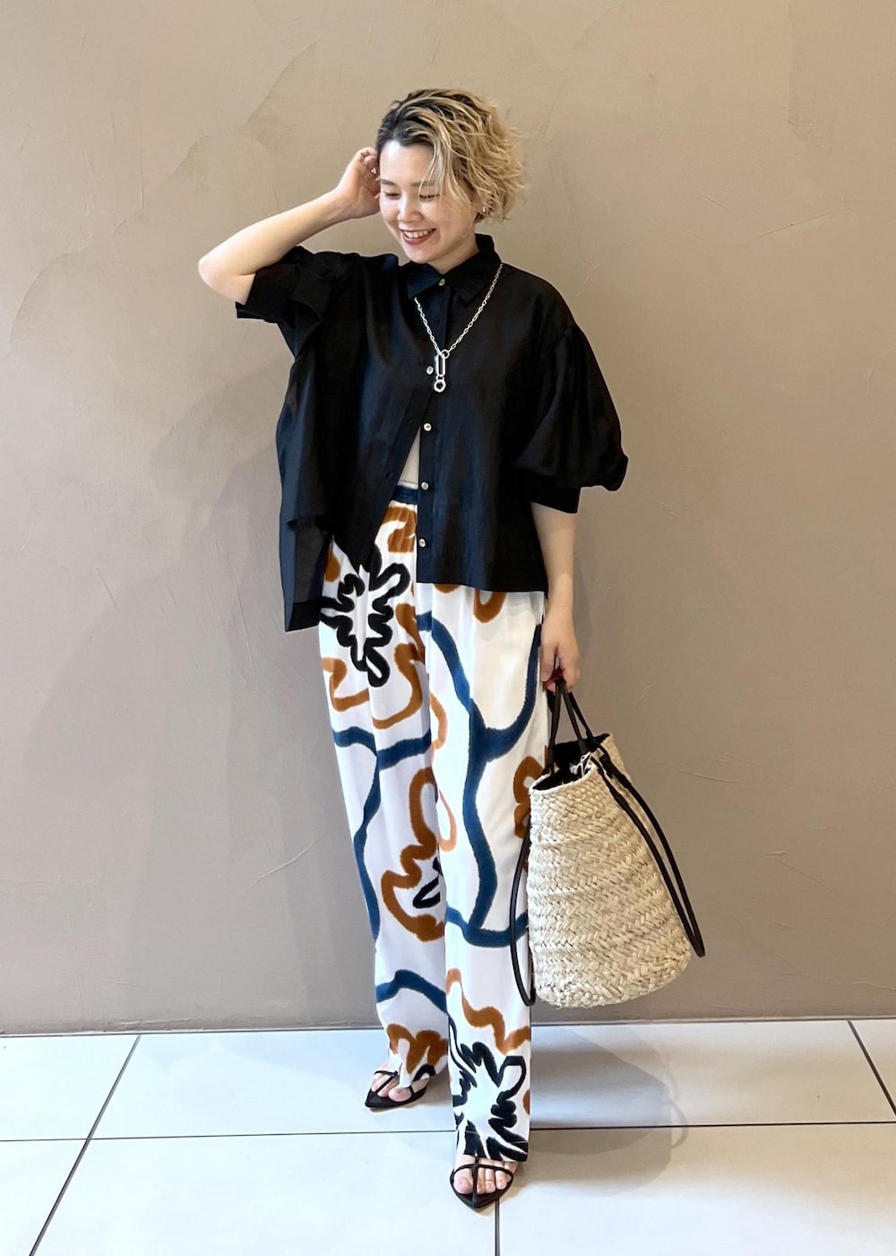 ブラック系のサンダル、ホワイト系のかごバッグ、ブラック系のシャツ/ブラウスを着用したレディースの春コーディネートの2枚目の写真