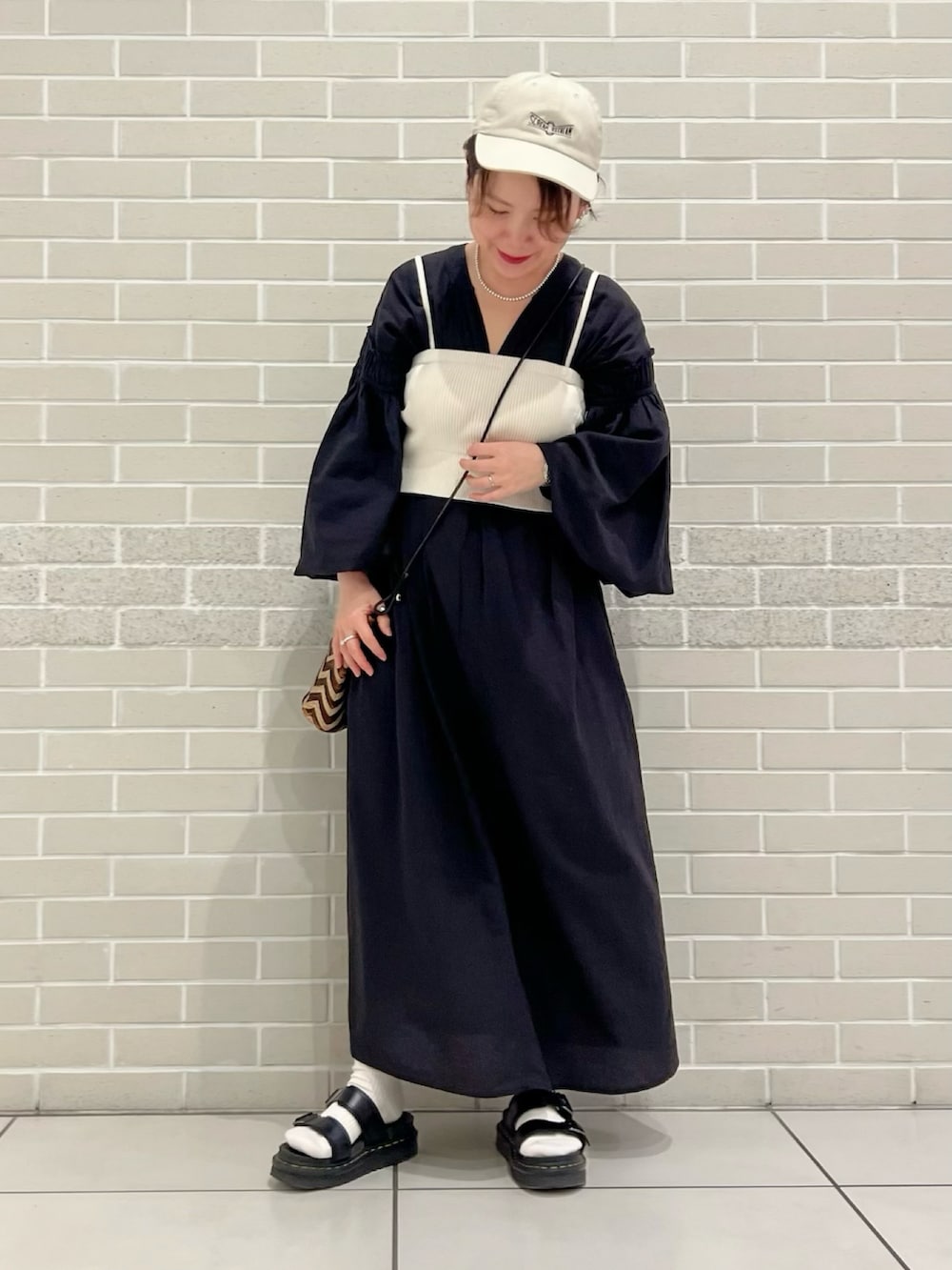 ブラック系のワンピース、ホワイト系のチューブトップ、ベージュ系のワンピースを着用したレディースの春コーディネートの2枚目の写真