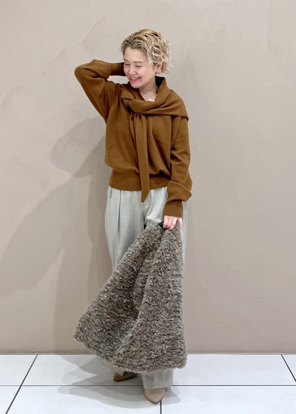 ベージュ系のスラックス、ブラウン系のトートバッグ、イエロー系のニット/セーターを着用したレディースの秋コーディネートの3枚目の写真