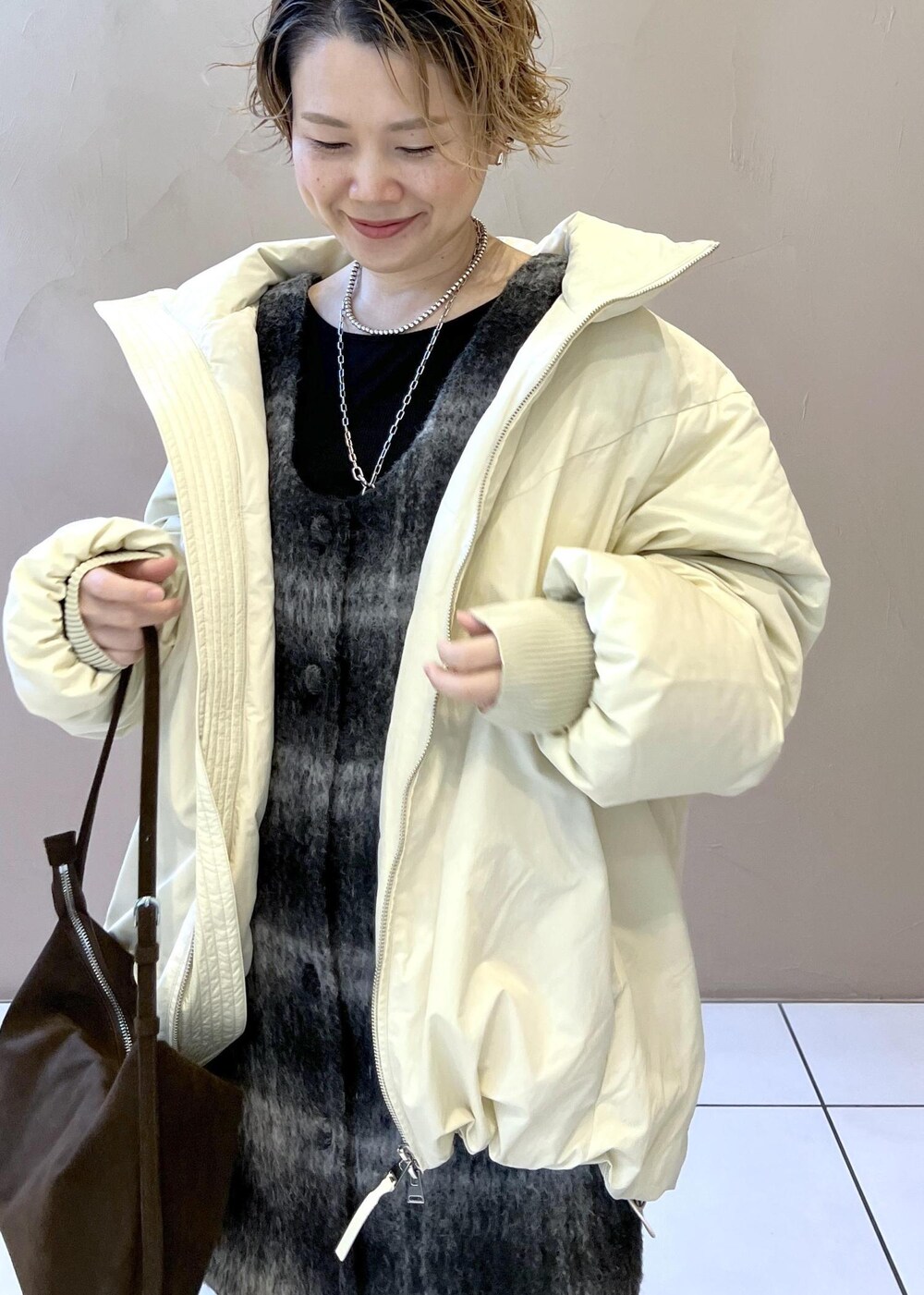 ホワイト系のダウンジャケット/コート、グレー系のジャンパースカート、ブラウン系のショルダーバッグを着用したレディースの秋コーディネートの8枚目の写真