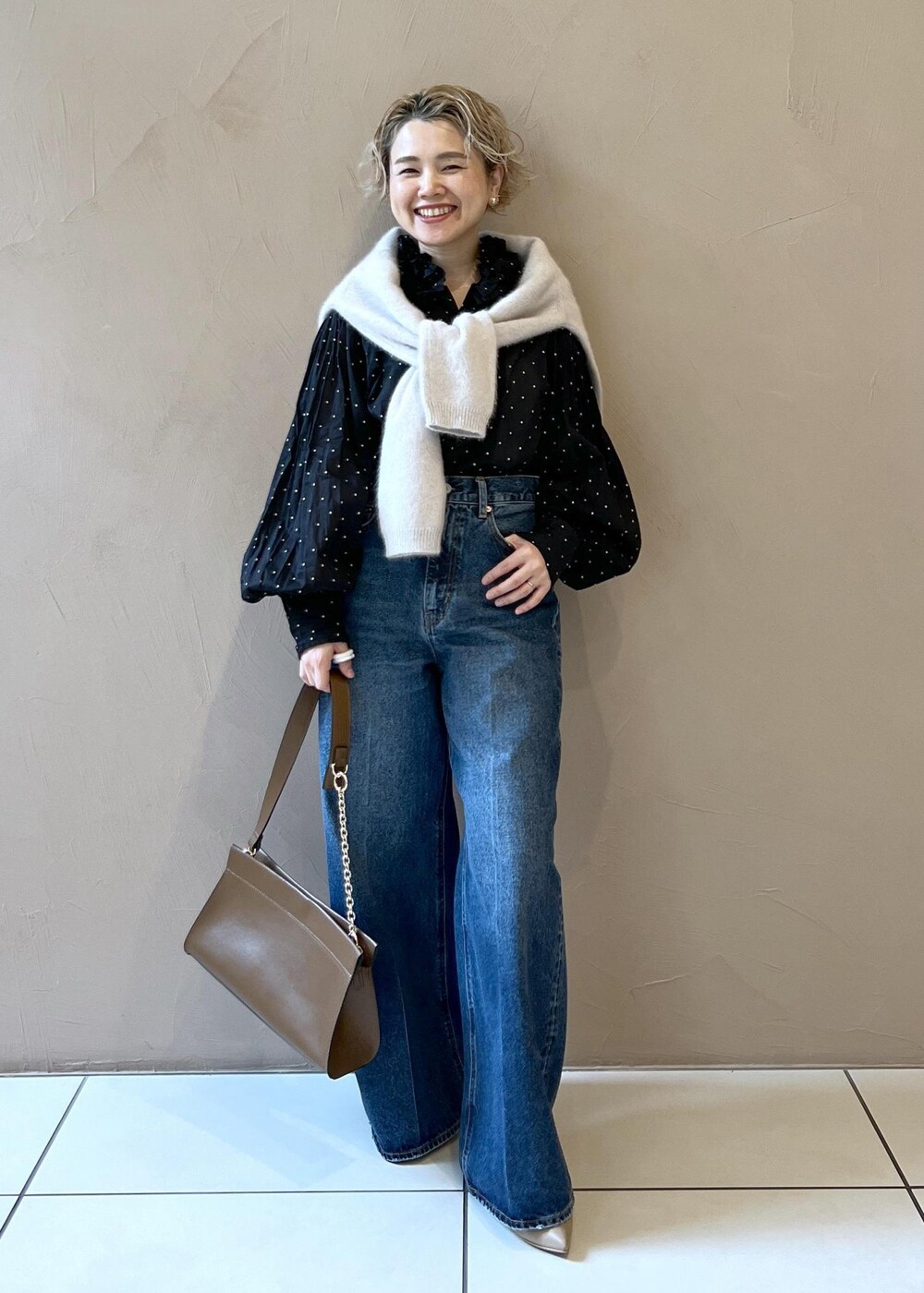 グレー系のニット/セーター、ブルー系のデニムパンツ、ブラウン系のショルダーバッグを着用したレディースの秋コーディネートの3枚目の写真