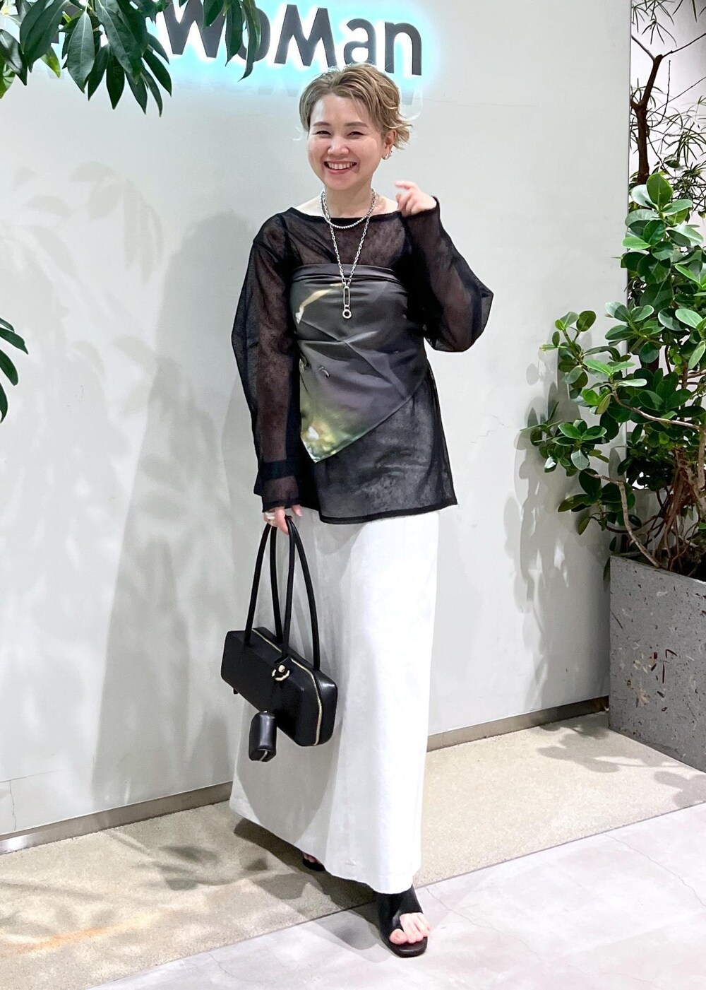 ホワイト系のスカート、ブラック系のサンダル、ブラック系のショルダーバッグを着用したレディースの夏コーディネートの3枚目の写真