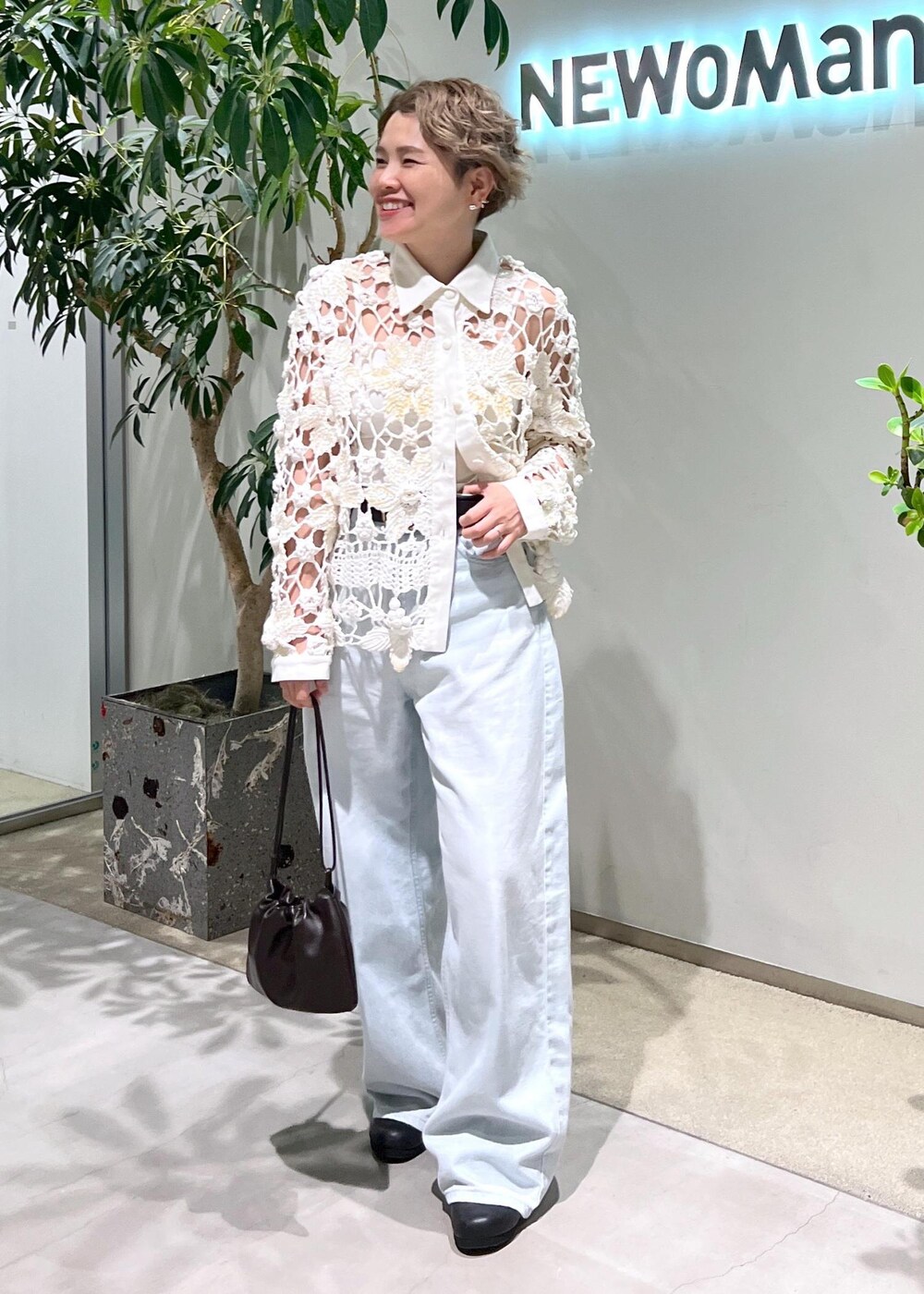 ブルー系のデニムパンツ、ブラウン系のハンドバッグを着用したレディースの夏コーディネートの3枚目の写真