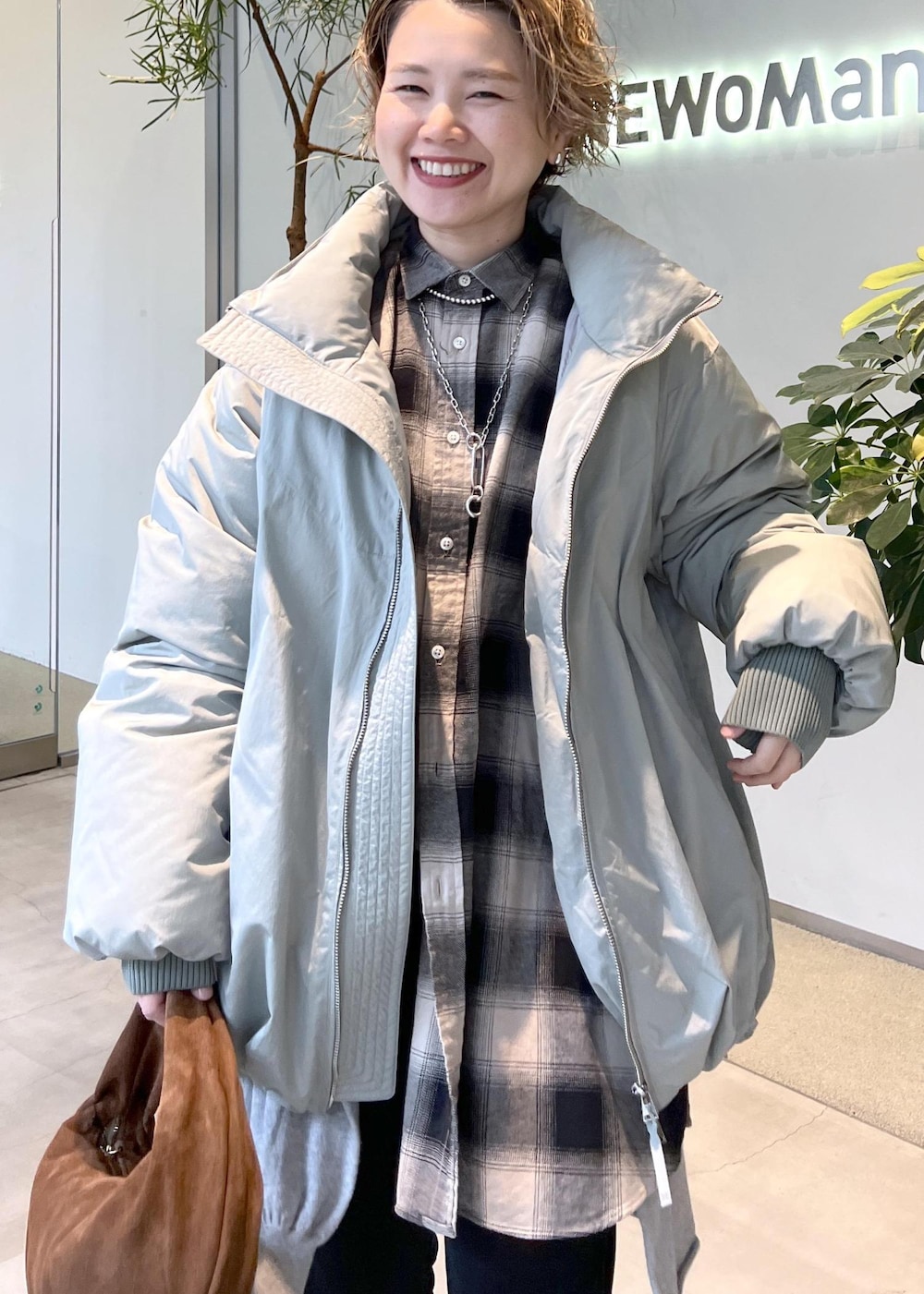 グリーン系のダウンジャケット/コート、ブラウン系のハンドバッグ、ブラック系のブーツを着用したレディースの秋コーディネートの6枚目の写真