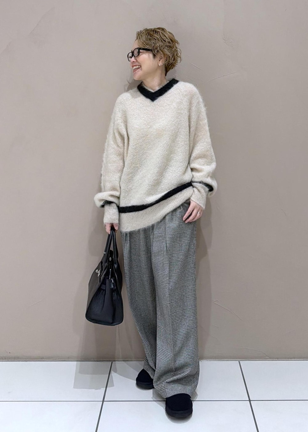 グレー系のスラックス、ブラック系のブーツを着用したレディースの冬コーディネートの2枚目の写真