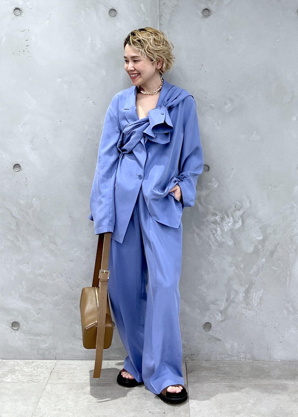 ブラウン系のショルダーバッグ、ブラウン系のサンダル、ブルー系のテーラードジャケットを着用したレディースの冬コーディネートの2枚目の写真