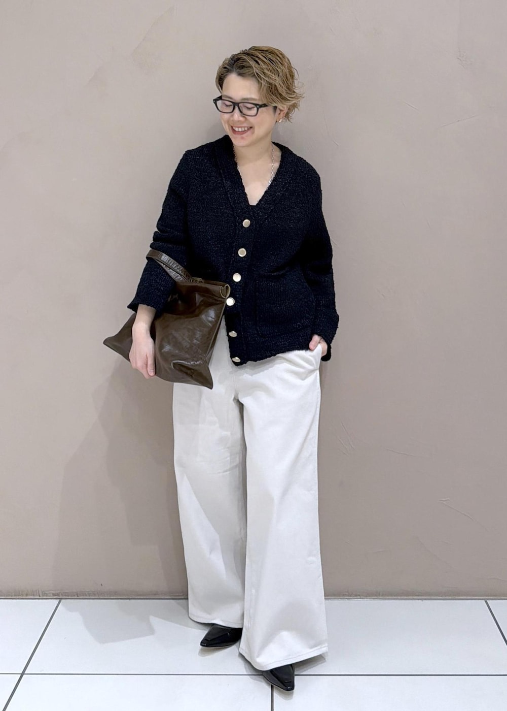 ブラック系のカーディガン/ボレロ、ホワイト系のサロペット/オーバーオール、ブラック系のローファーを着用したレディースの冬コーディネートの2枚目の写真