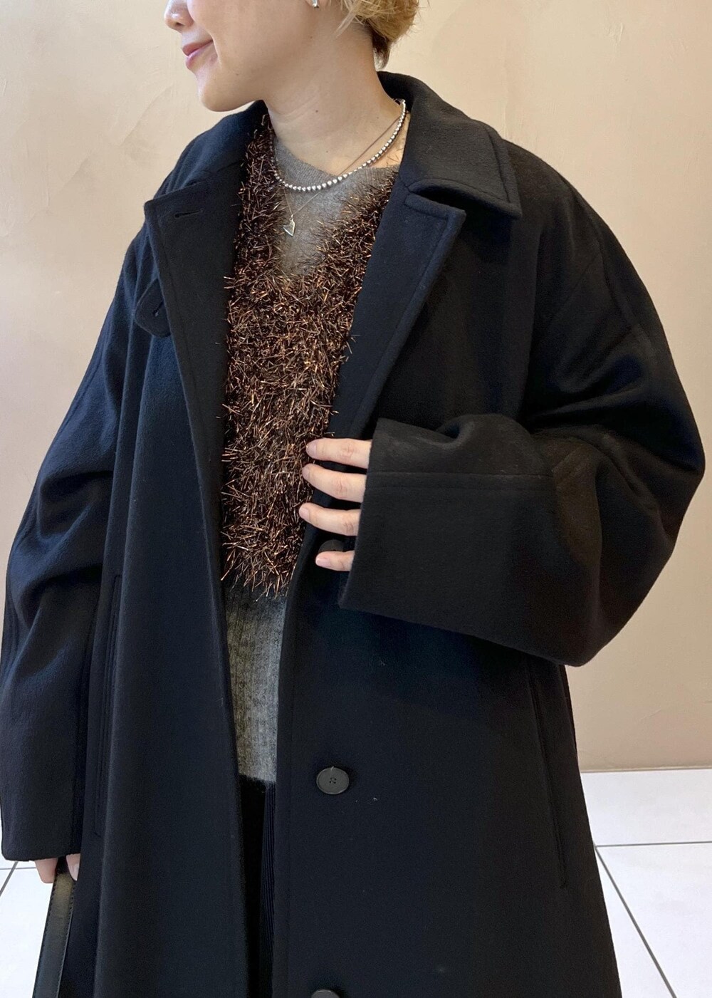 ブラック系のベスト、グレー系のニット/セーター、ブラック系のステンカラーコートを着用したレディースの冬コーディネートの5枚目の写真