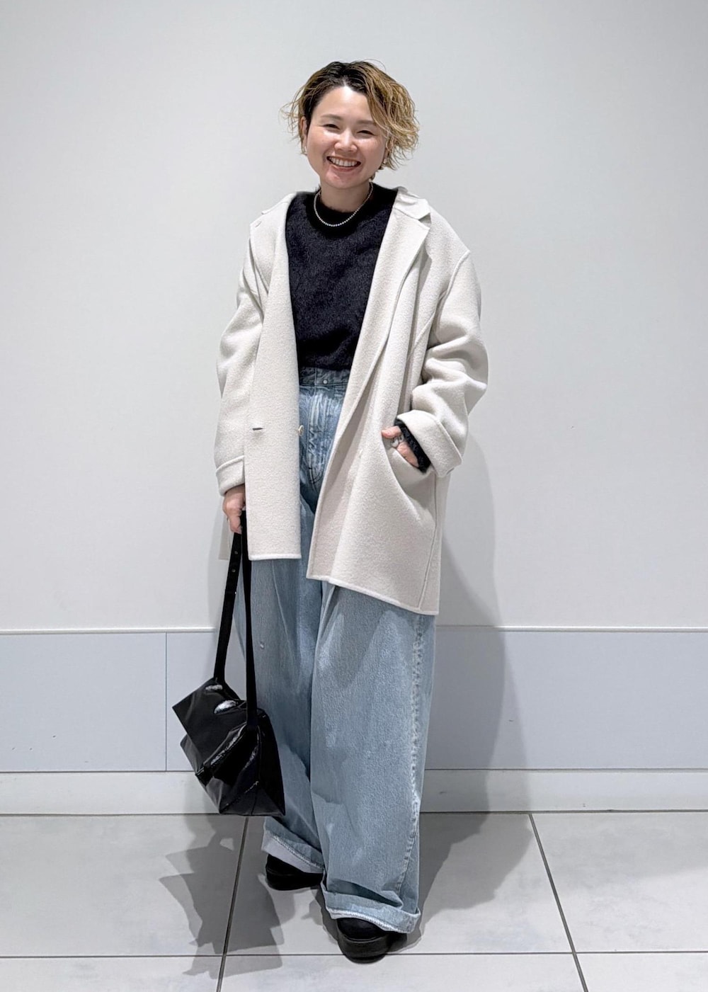 ブラック系のショルダーバッグ、ホワイト系のその他アウター、ブラック系のブーツを着用したレディースの秋コーディネートの2枚目の写真