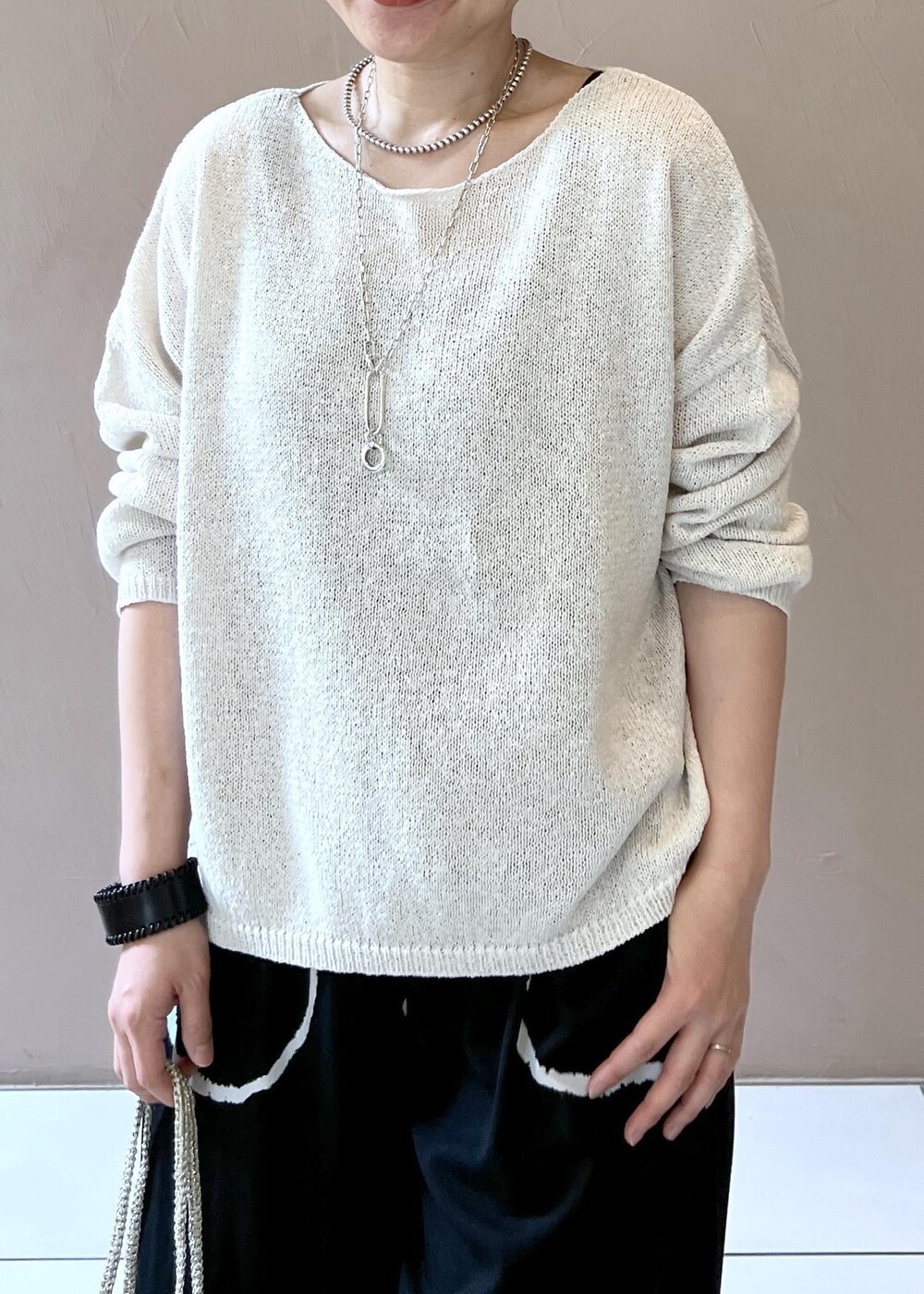 ゴールド系のハンドバッグ、シルバー系のサンダル、ホワイト系のニット/セーターを着用したレディースの春コーディネートの5枚目の写真