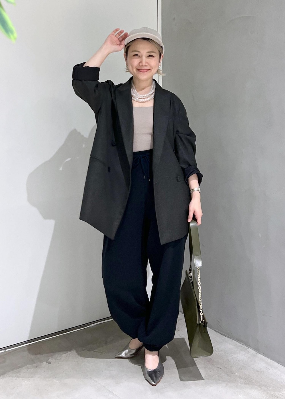 グリーン系のショルダーバッグ、ブラック系のスウェットパンツ、シルバー系のパンプスを着用したレディースの秋コーディネートの3枚目の写真