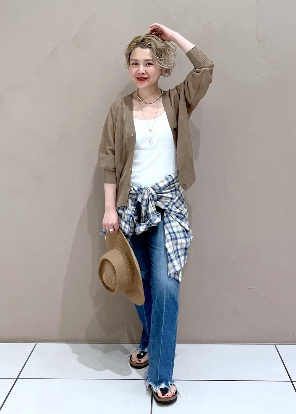 ホワイト系のタンクトップ、ゴールド系のカーディガン/ボレロ、ブルー系のデニムパンツを着用したレディースの夏コーディネートの3枚目の写真