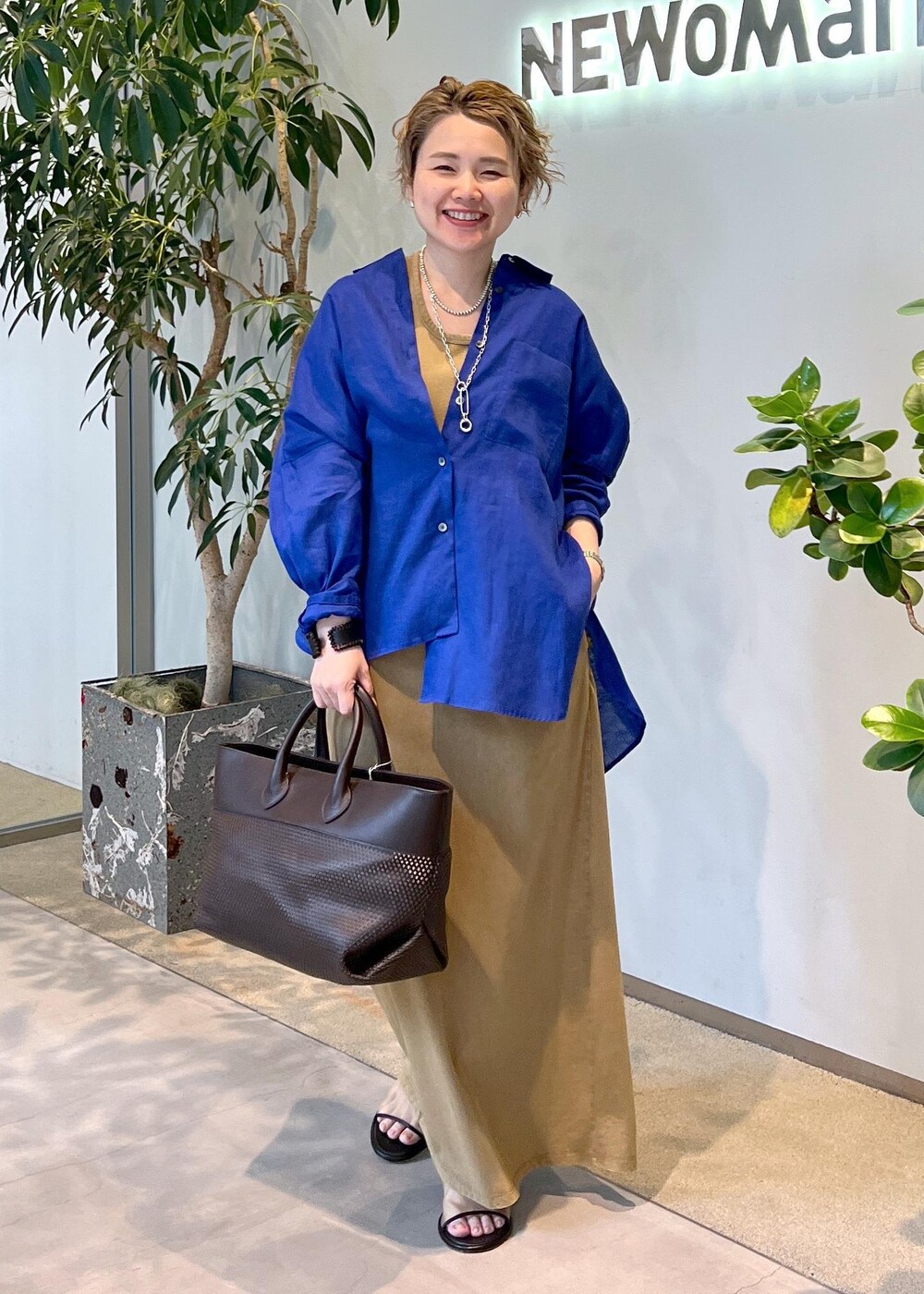 ブルー系のシャツ/ブラウス、ブラウン系のトートバッグ、ブラウン系のワンピースを着用したレディースの夏コーディネートの3枚目の写真
