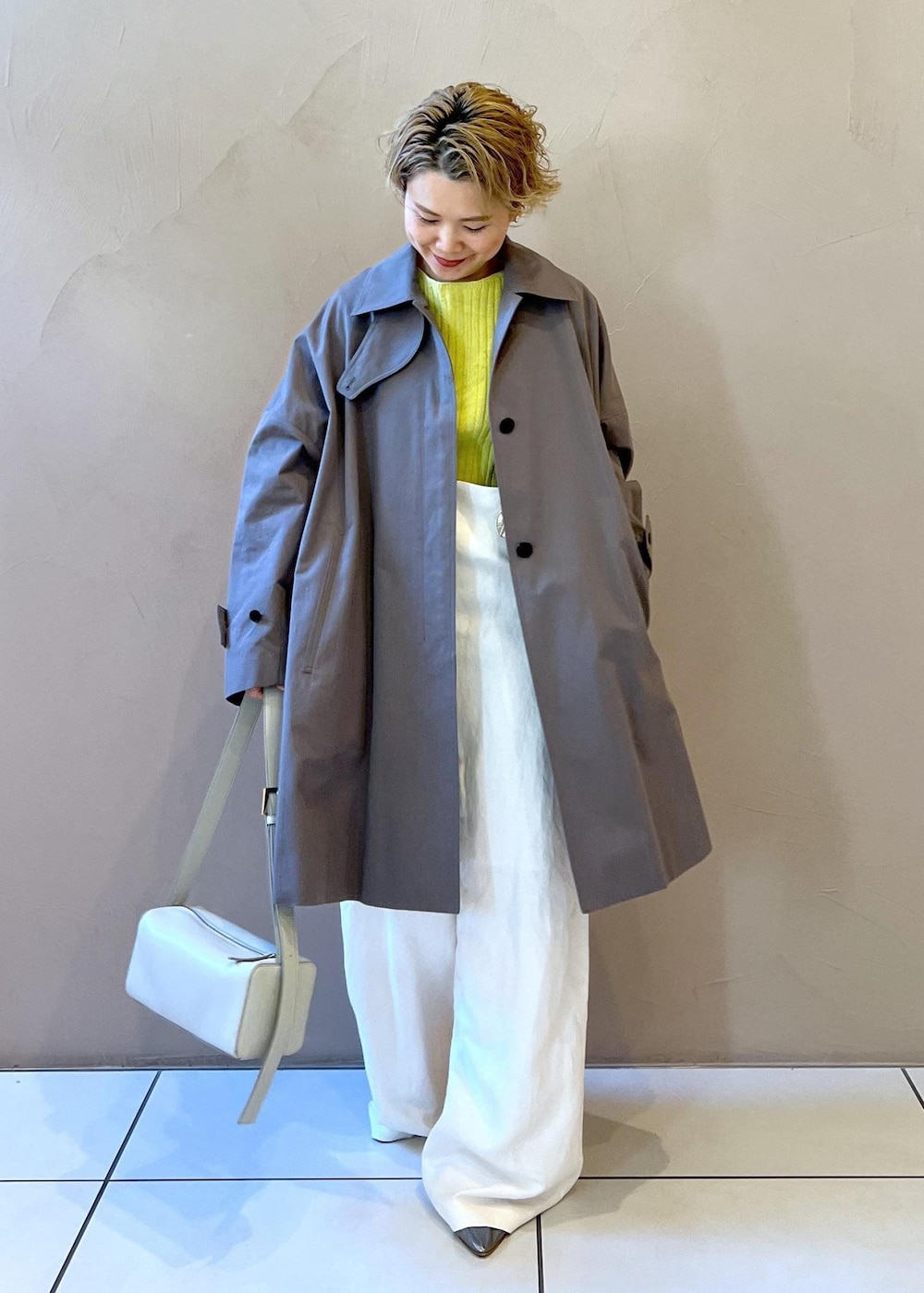 シルバー系のショルダーバッグ、イエロー系のカーディガン/ボレロ、ホワイト系のサロペット/オーバーオールを着用したレディースの冬コーディネートの3枚目の写真