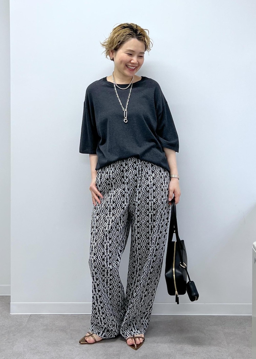 グレー系のTシャツ/カットソー、その他のサンダル、ブラック系のショルダーバッグを着用したレディースの春コーディネートの2枚目の写真