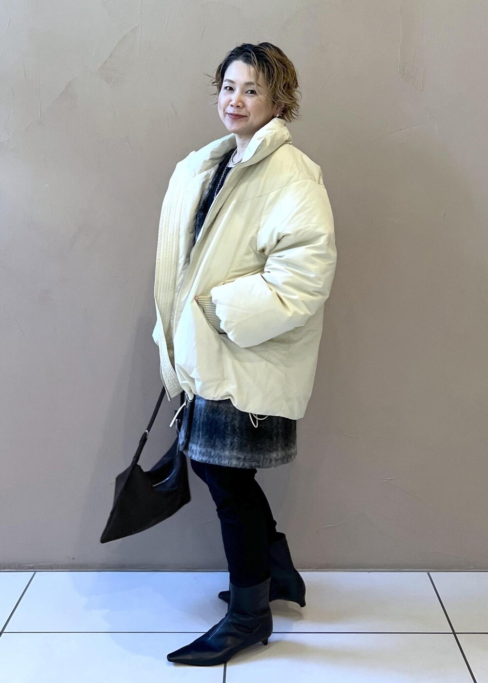 ホワイト系のダウンジャケット/コート、グレー系のジャンパースカート、ブラウン系のショルダーバッグを着用したレディースの秋コーディネートの6枚目の写真