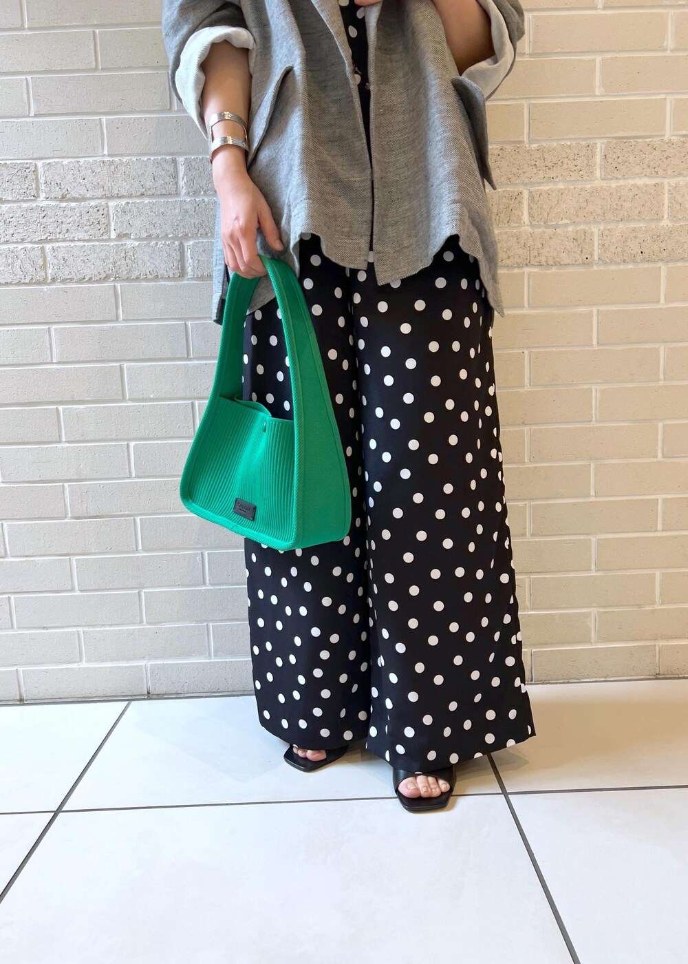ホワイト系のタンクトップ、グリーン系のハンドバッグ、ブラック系のサンダルを着用したレディースの夏コーディネートの7枚目の写真