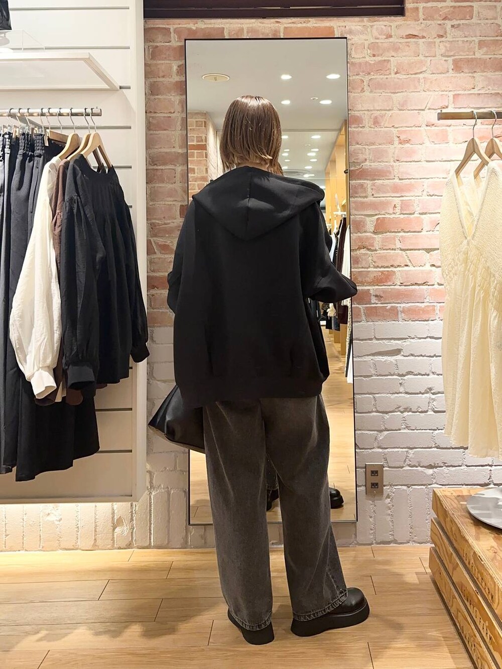 グレー系のデニムパンツ、ブラック系のパーカー、ブラック系のサンダルを着用したレディースの秋コーディネートの3枚目の写真