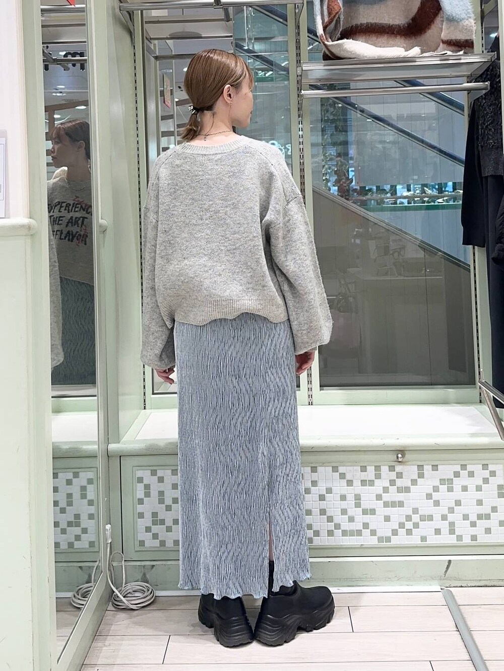 ブラック系のブーツ、ブルー系のスカート、ブラック系のショルダーバッグを着用したレディースの秋コーディネートの2枚目の写真