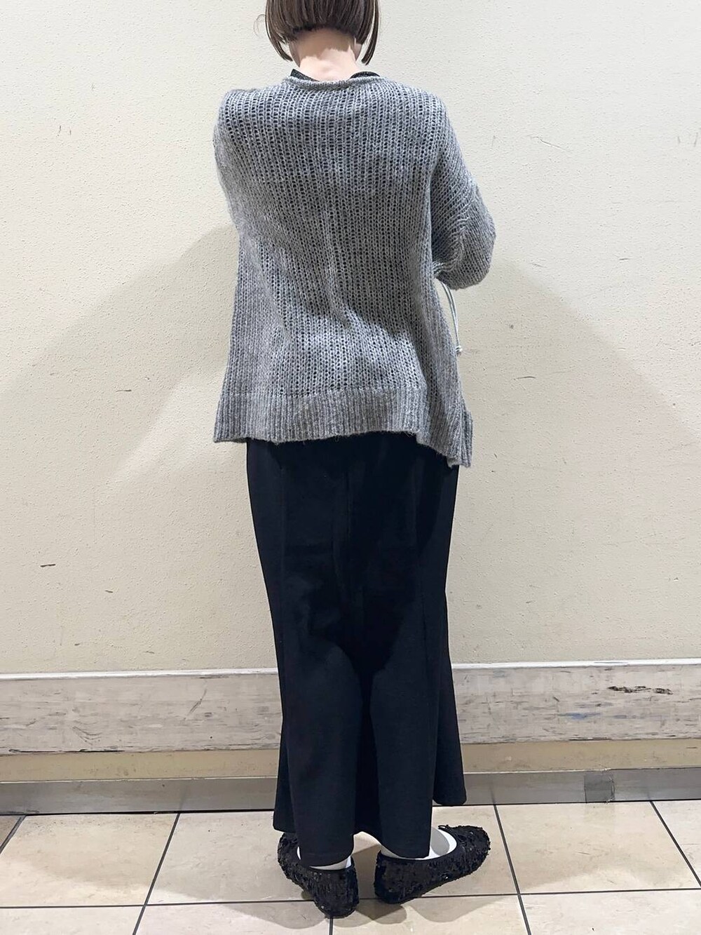 ブラック系のスカート、ブラック系のTシャツ/カットソー、グレー系のニット/セーターを着用したレディースの冬コーディネートの2枚目の写真