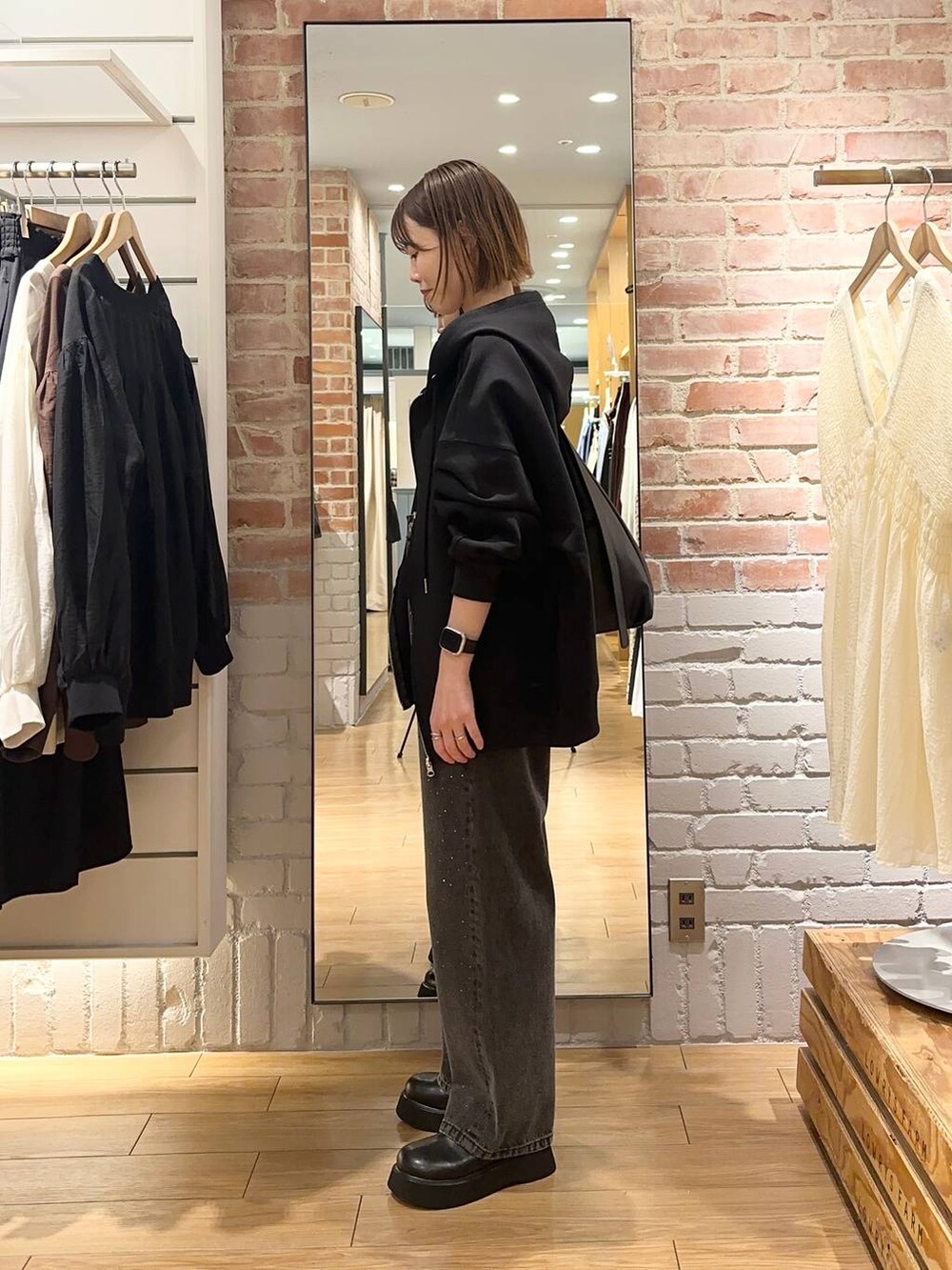 グレー系のデニムパンツ、ブラック系のパーカー、ブラック系のサンダルを着用したレディースの秋コーディネートの2枚目の写真