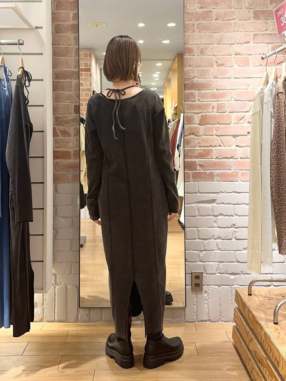 ブラック系のブーツ、シルバー系のトートバッグ、グレー系のワンピースを着用したレディースの冬コーディネートの2枚目の写真