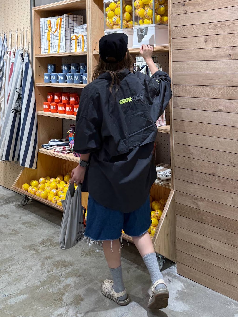 ブルー系のデニムパンツ、グレー系のエコバッグ/サブバッグ、ブラック系のキャップを着用したレディースの春コーディネートの4枚目の写真