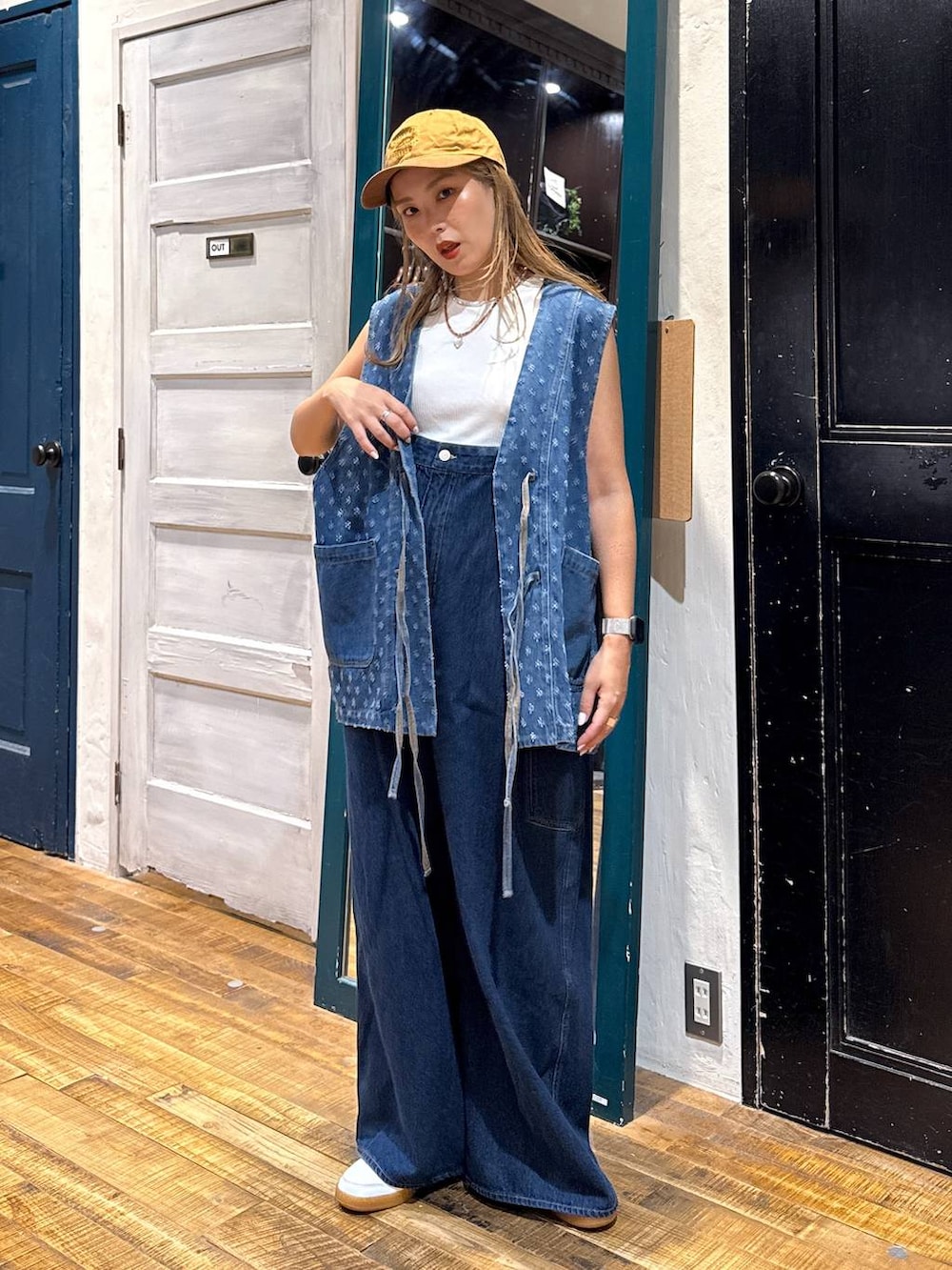 ホワイト系のタンクトップ、イエロー系のキャップを着用したレディースの夏コーディネートの2枚目の写真