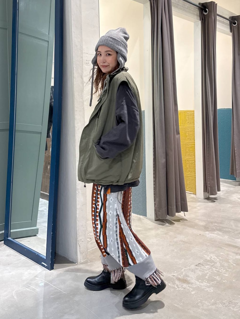 グリーン系のベスト、ブラック系のブーツを着用したレディースの秋コーディネートの4枚目の写真