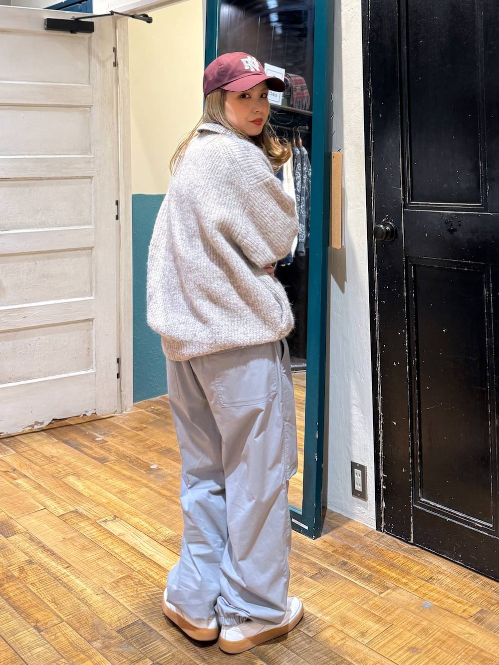 グレー系のその他パンツ、ベージュ系のカーディガン/ボレロ、レッド系のキャップを着用したレディースの冬コーディネートの4枚目の写真