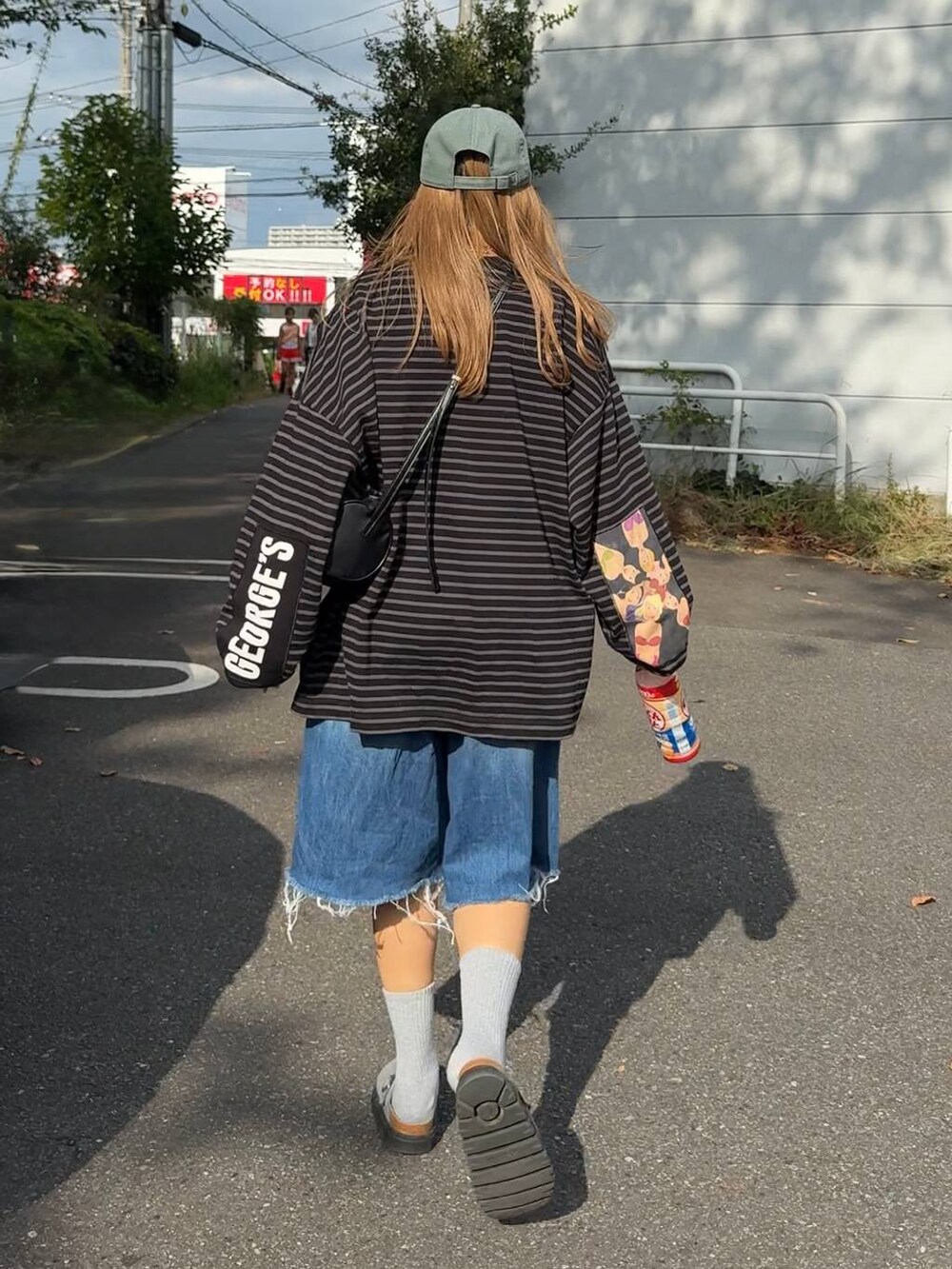 ブルー系のデニムパンツ、グリーン系のキャップを着用したレディースの秋コーディネートの2枚目の写真