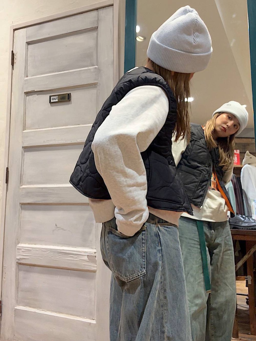 ブラック系のベスト、ベージュ系のスウェット、ブルー系のデニムパンツを着用したレディースの冬コーディネートの2枚目の写真