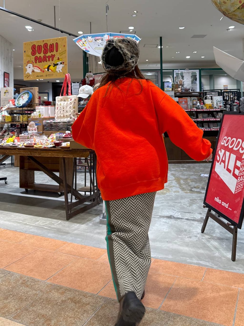 オレンジ系のスウェット、ブラウン系のブーツ、ブラウン系のスカートを着用したレディースの冬コーディネートの4枚目の写真