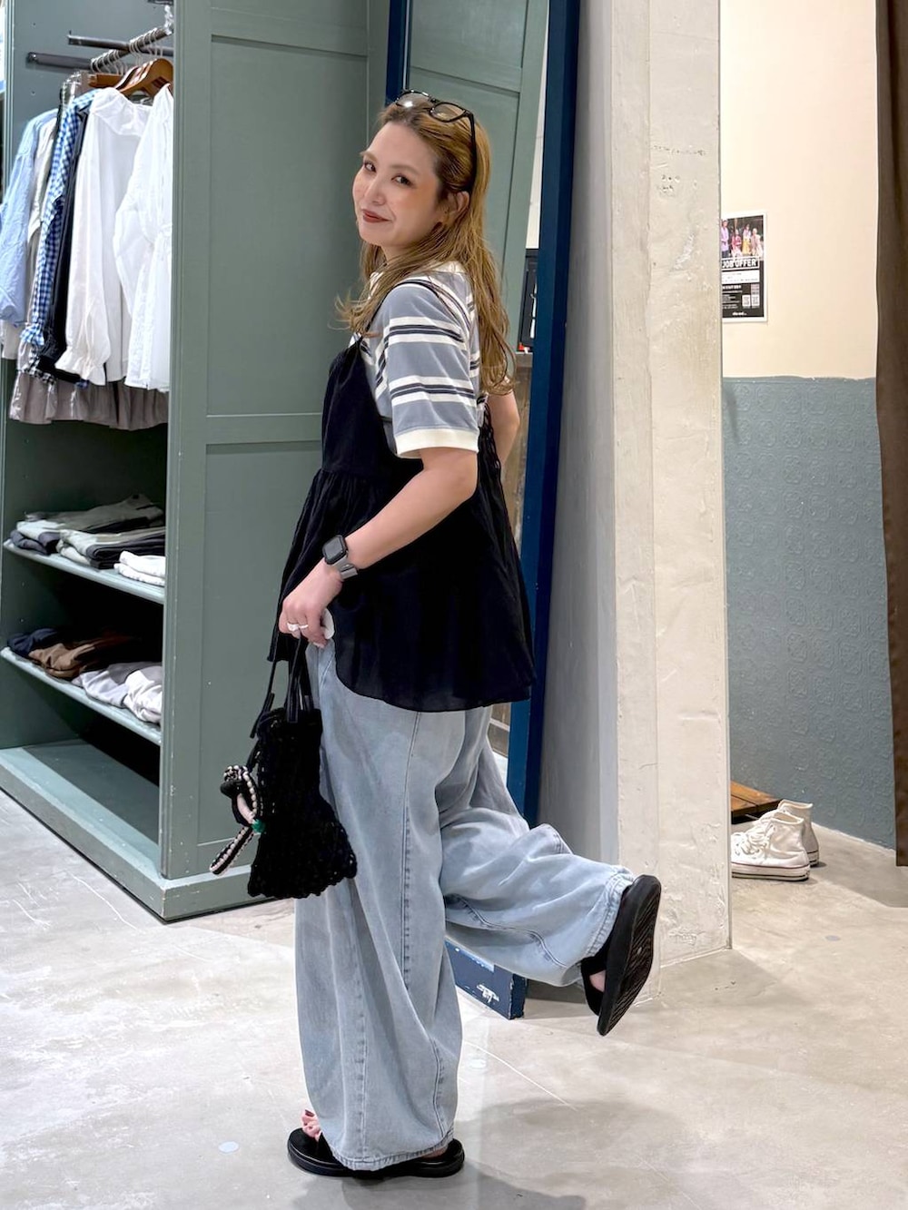 ブルー系のデニムパンツ、ブラック系のトートバッグ、ブラック系のキャミソールを着用したレディースの春コーディネートの3枚目の写真