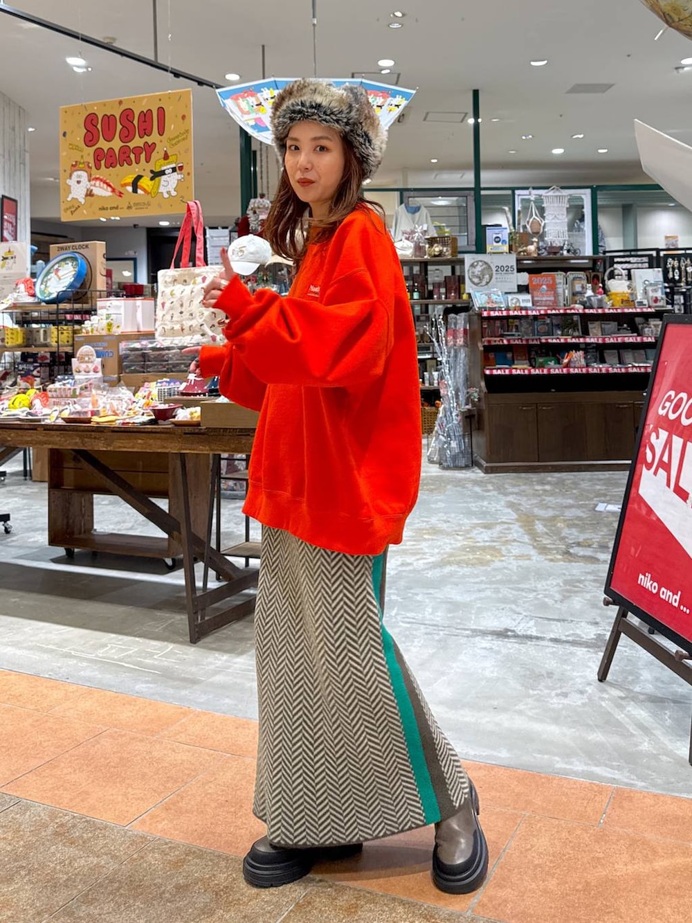 オレンジ系のスウェット、ブラウン系のブーツ、ブラウン系のスカートを着用したレディースの冬コーディネートの3枚目の写真