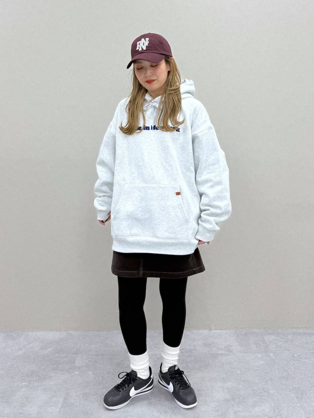 ブラウン系のスカート、グレー系のパーカー、レッド系のキャップを着用したレディースの秋コーディネートの3枚目の写真