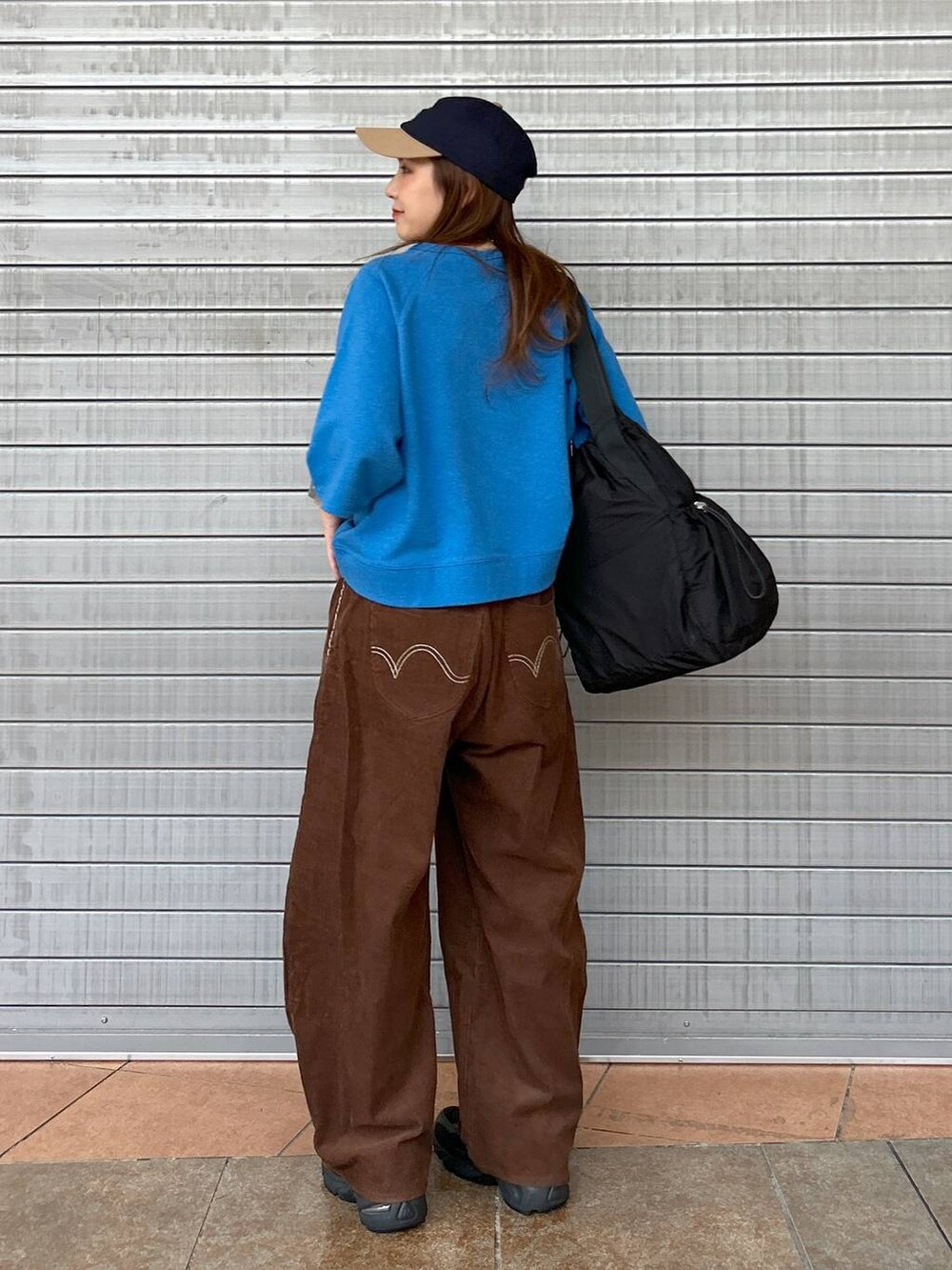 ブラック系のスニーカー、ブルー系のTシャツ/カットソー、ブラック系のトートバッグを着用したレディースの秋コーディネートの5枚目の写真