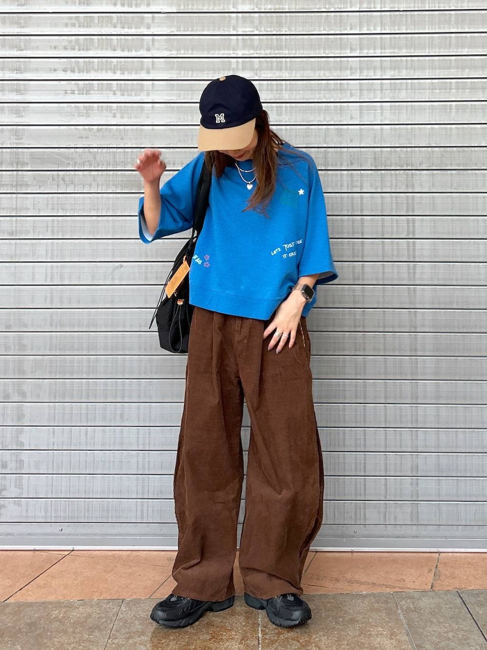 ブラック系のスニーカー、ブルー系のTシャツ/カットソー、ブラック系のトートバッグを着用したレディースの秋コーディネートの2枚目の写真