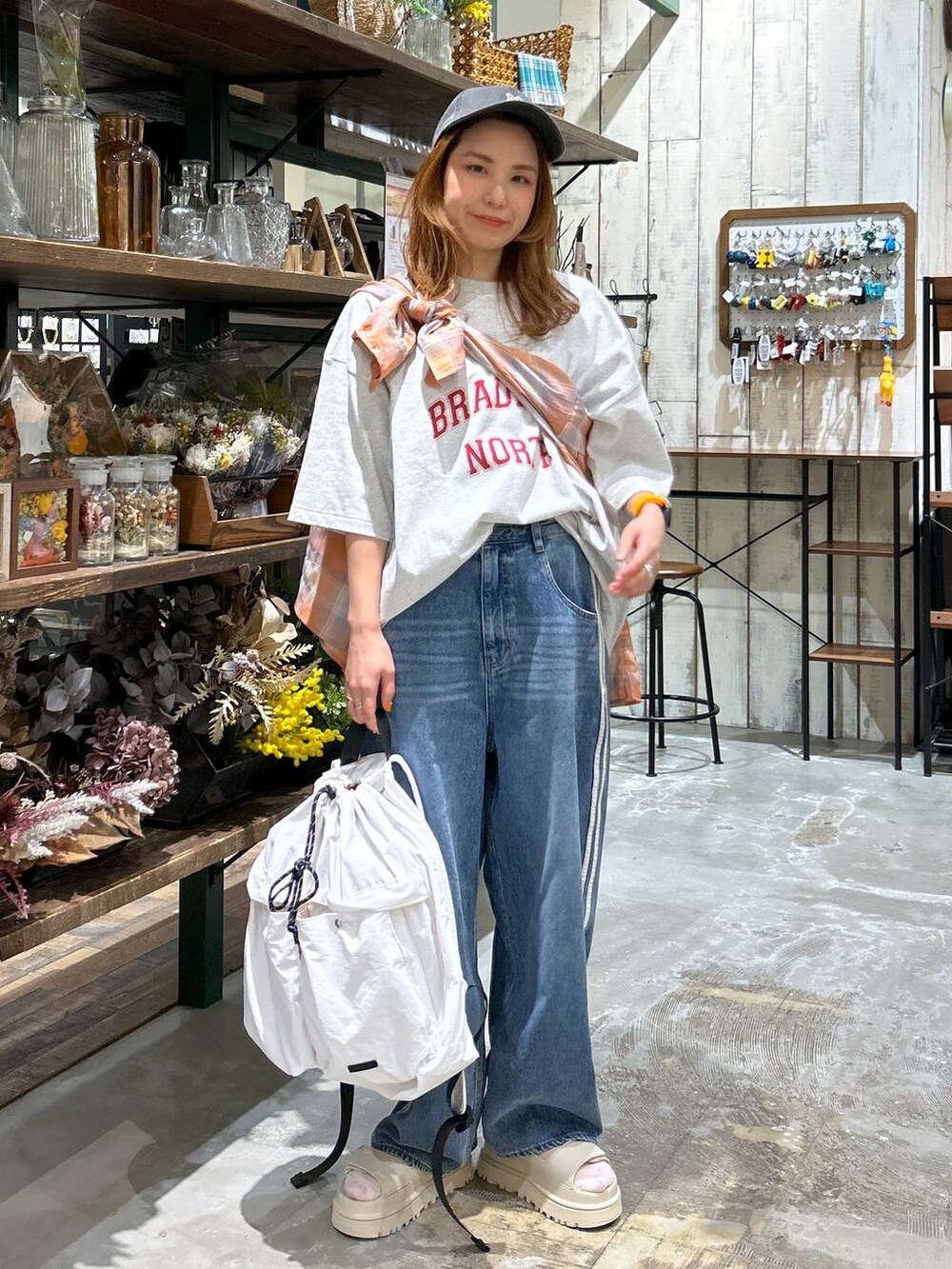 ベージュ系のバックパック/リュック、オレンジ系のシャツ/ブラウス、グレー系のTシャツ/カットソーを着用したレディースの春コーディネートの2枚目の写真