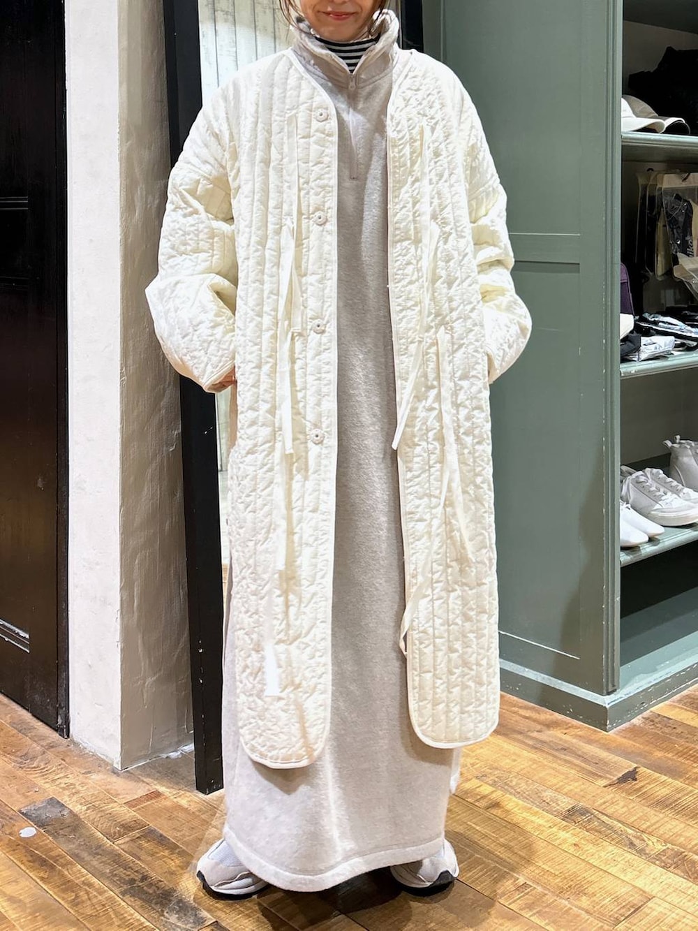 ホワイト系のノーカラーコート、ホワイト系のTシャツ/カットソー、ベージュ系のワンピースを着用したレディースの冬コーディネートの3枚目の写真