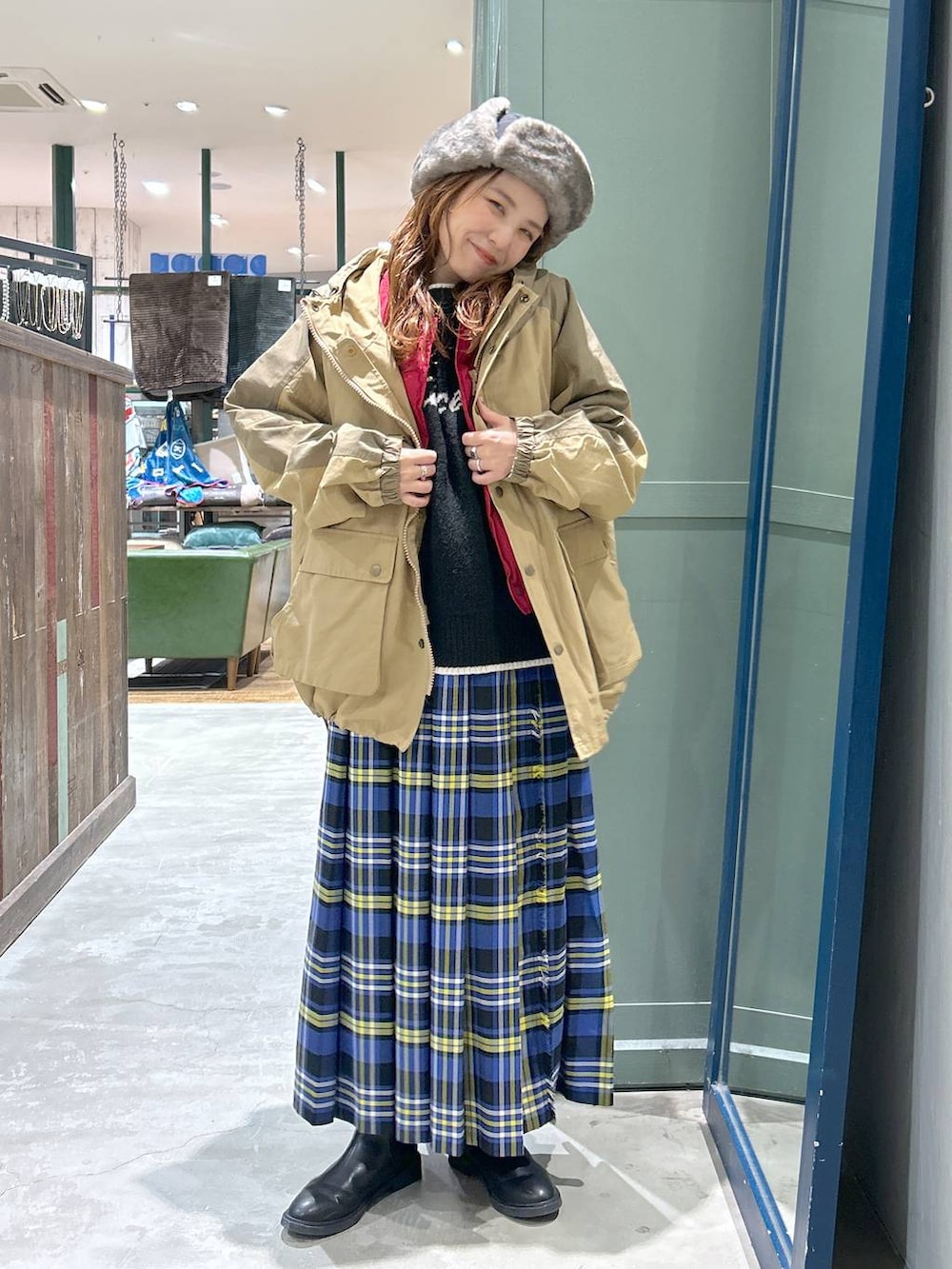 ブルー系のスカート、ベージュ系のマウンテンパーカー、ブラック系のニット/セーターを着用したレディースの冬コーディネートの2枚目の写真