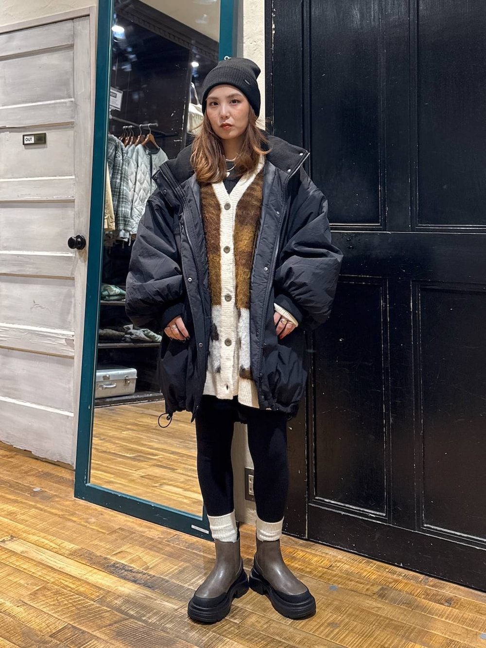ブラック系のナイロンジャケット、ブラウン系のブーツ、ブラウン系のカーディガン/ボレロを着用したレディースの秋コーディネートの2枚目の写真