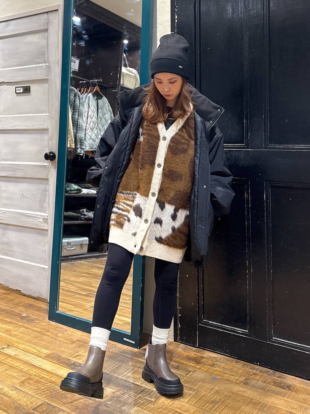 ブラック系のナイロンジャケット、ブラウン系のブーツ、ブラウン系のカーディガン/ボレロを着用したレディースの秋コーディネートの3枚目の写真