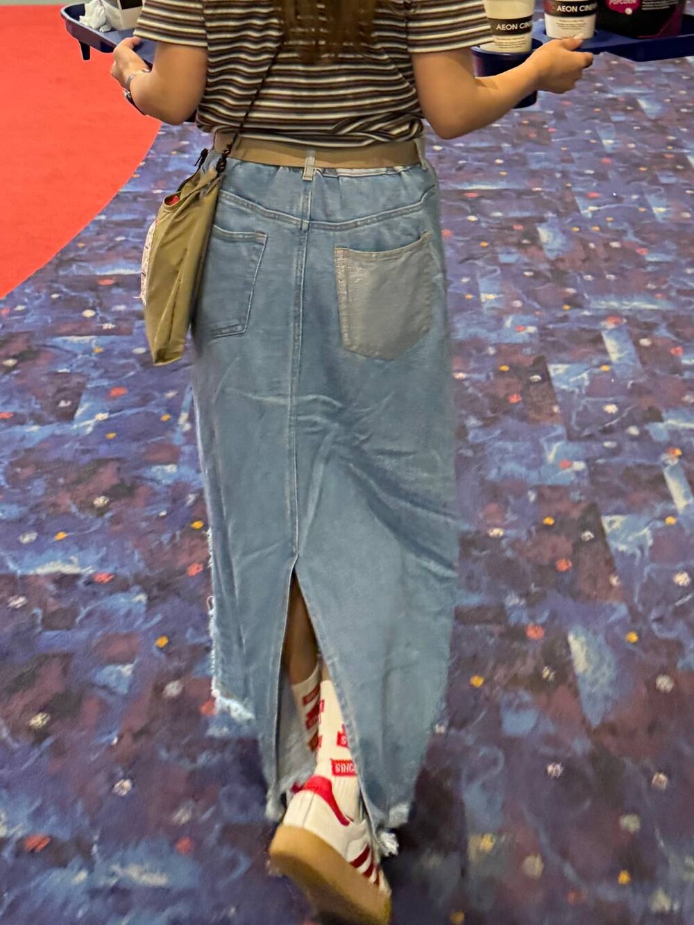 ベージュ系のショルダーバッグ、ブルー系のデニムスカート、ブラウン系のコインケースを着用したレディースの春コーディネートの4枚目の写真