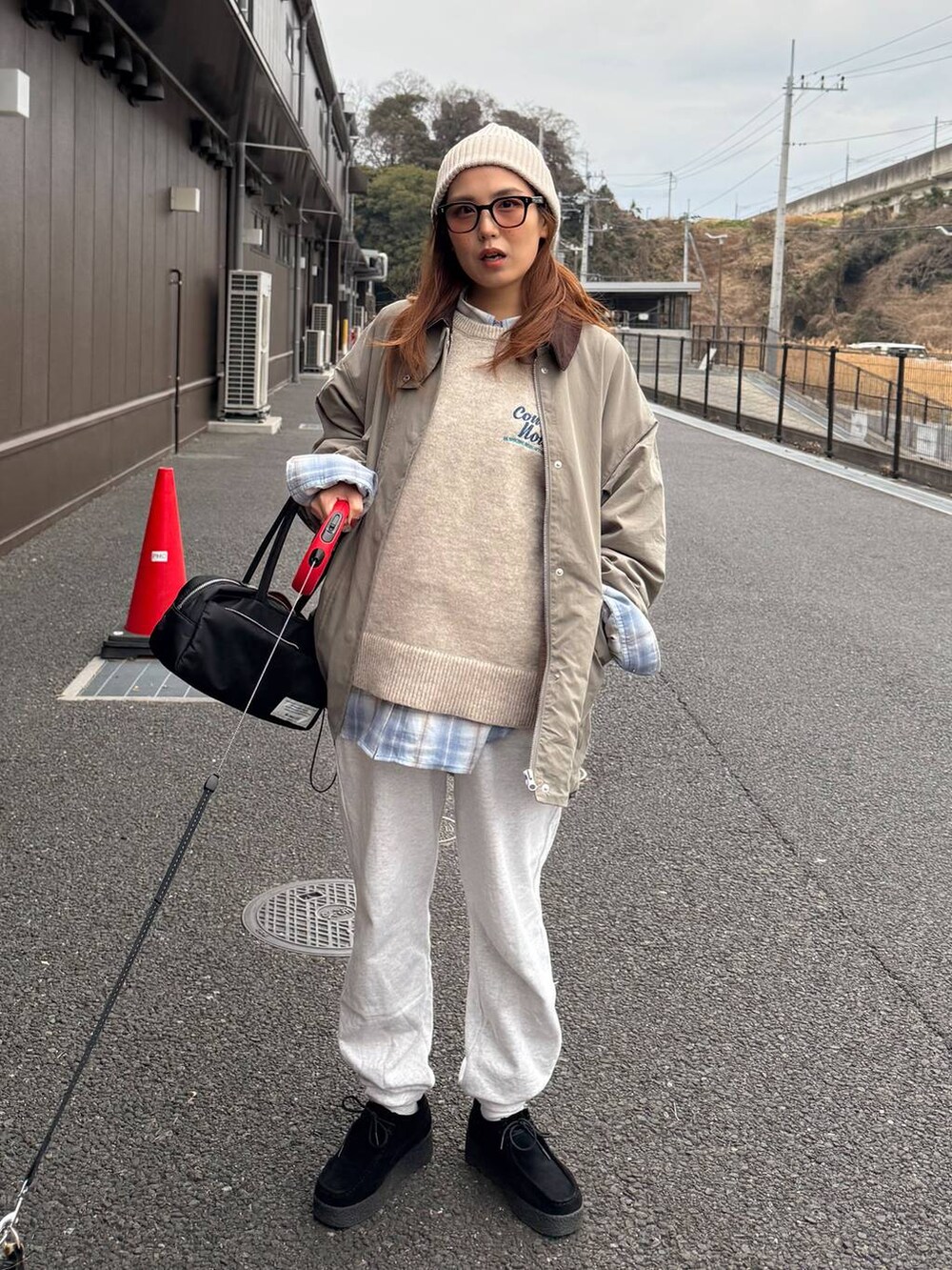 グレー系のスウェットパンツ、ベージュ系のニット/セーター、ブラック系のボストンバッグを着用したレディースの冬コーディネートの3枚目の写真