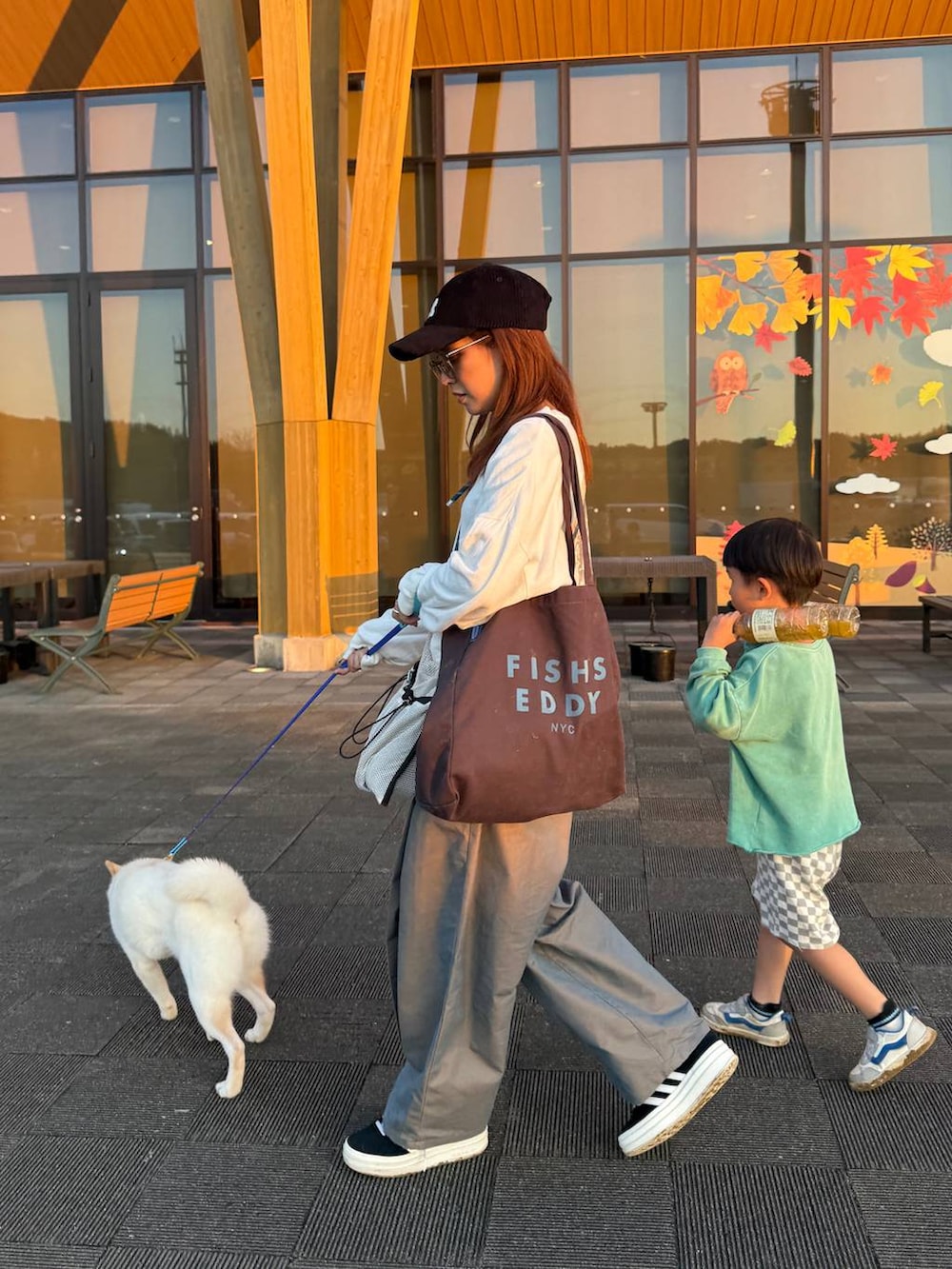 グリーン系のチノパンツ、グレー系のトートバッグ、ブラック系のキャップを着用したレディースの秋コーディネートの2枚目の写真