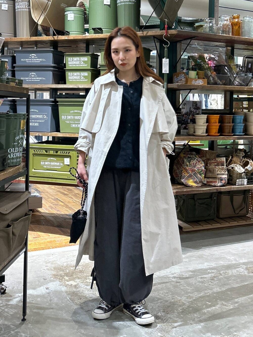 ブラック系のショルダーバッグ、グレー系のトレンチコート、ブラック系のシャツ/ブラウスを着用したレディースの春コーディネートの2枚目の写真