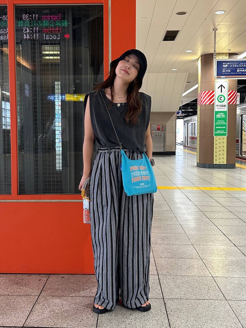 ブルー系のショルダーバッグ、ブラック系のその他パンツ、ブラック系のハットを着用したレディースの夏コーディネートの2枚目の写真