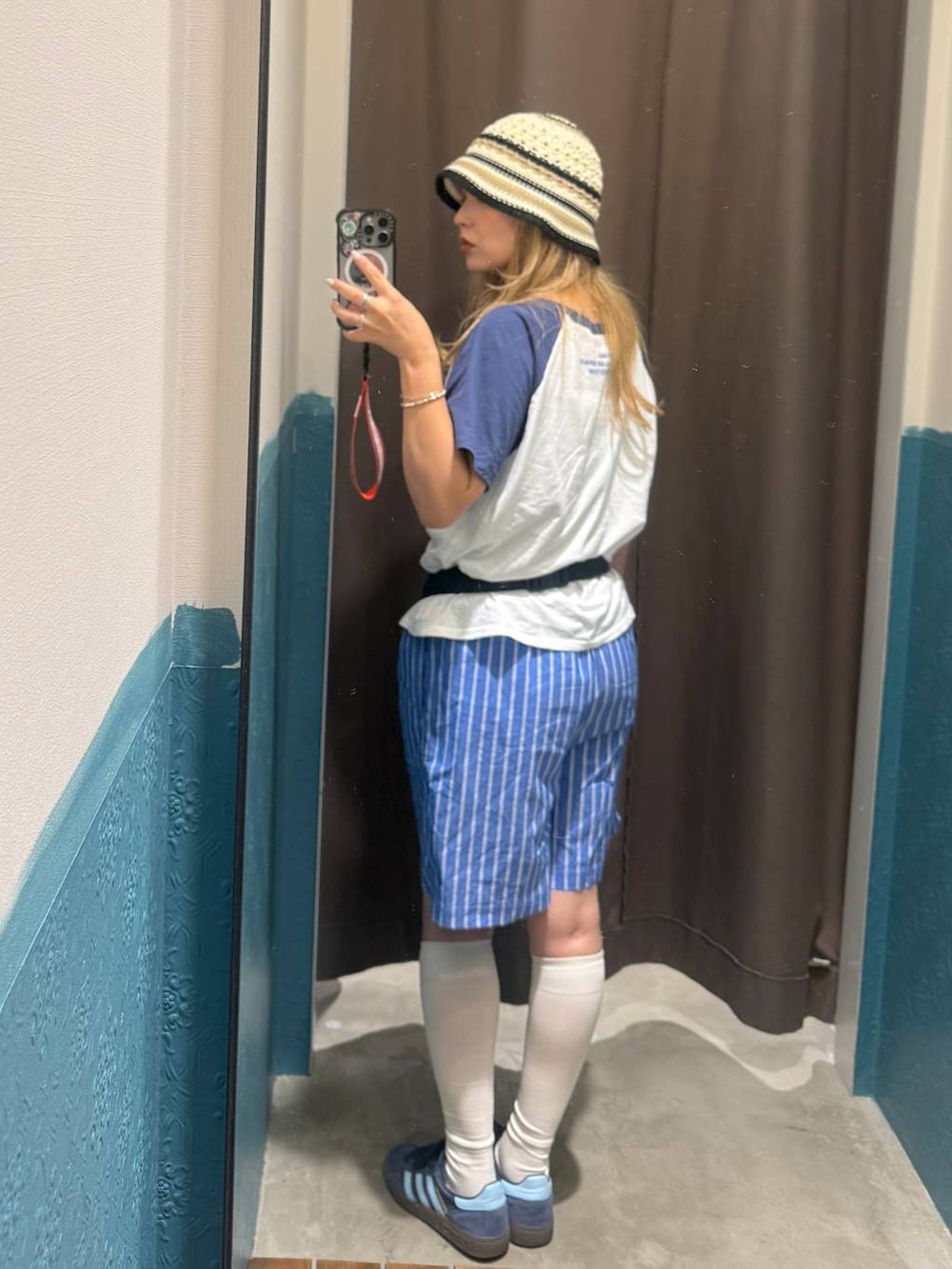 グレー系のボディバッグ/ウエストポーチ、ブルー系のTシャツ/カットソー、ベージュ系のハットを着用したレディースの夏コーディネートの3枚目の写真